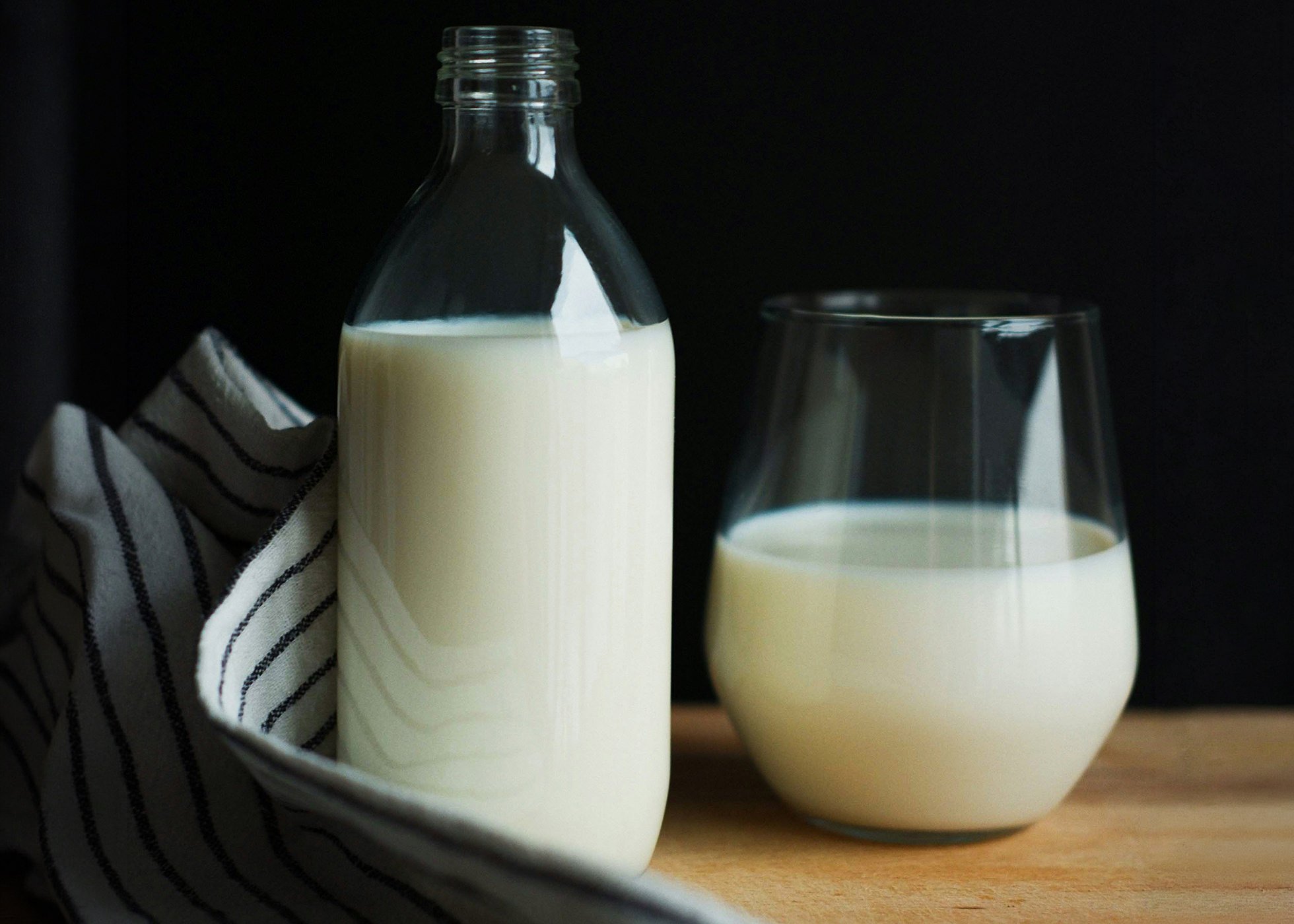 Glass bottle & glass both filled with milk on a slightly worn wooden table