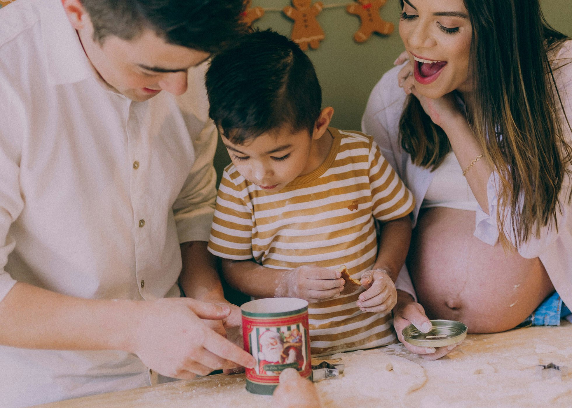 Pregnant woman & man baking in their kitchen with their young child