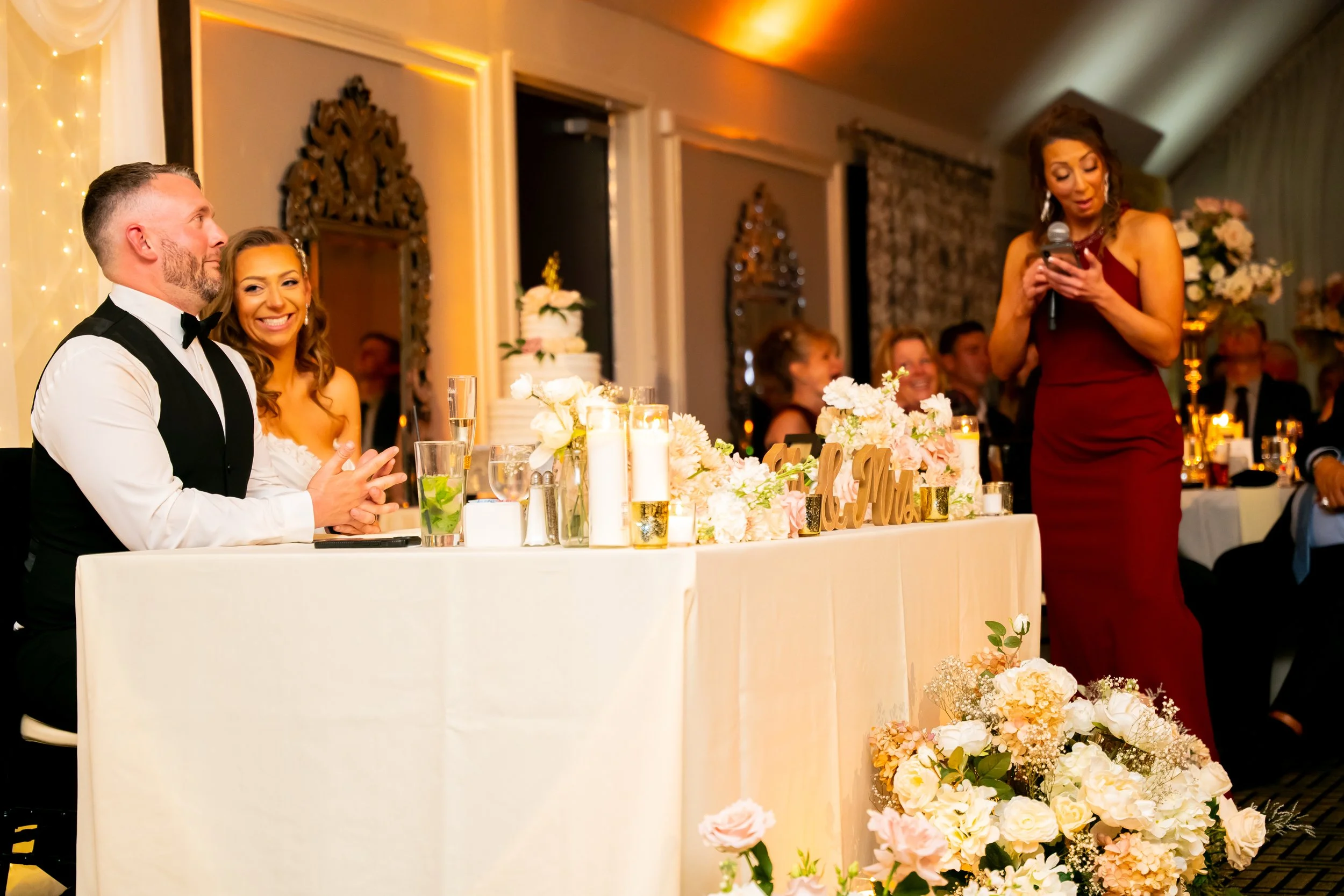 Newlywed couple smiling at their sweetheart table during a wedding reception at Novellas