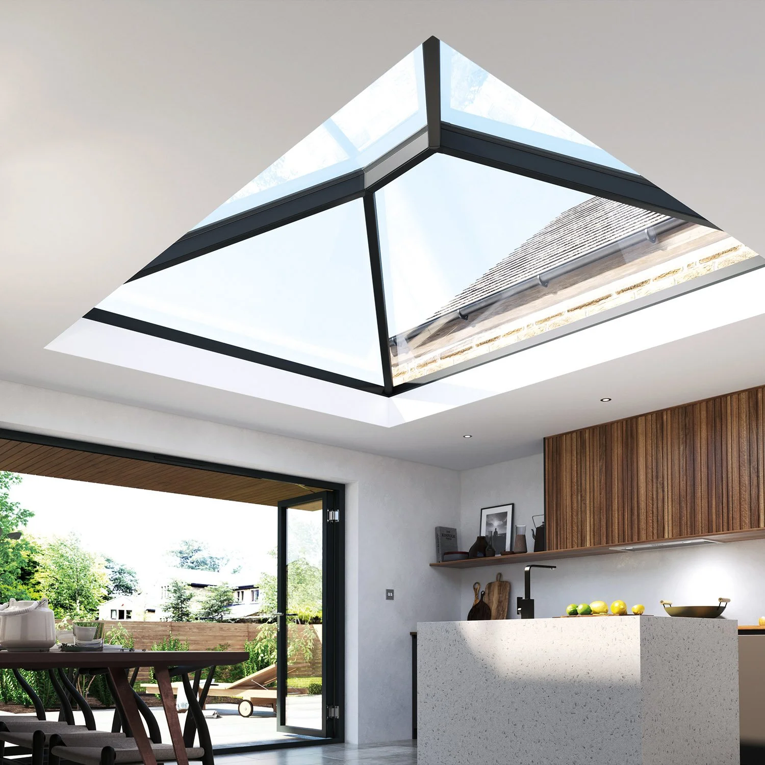 Modern kitchen with a large skylight above, white walls, wooden cabinets, and a sliding glass door leading to an outdoor patio with greenery.