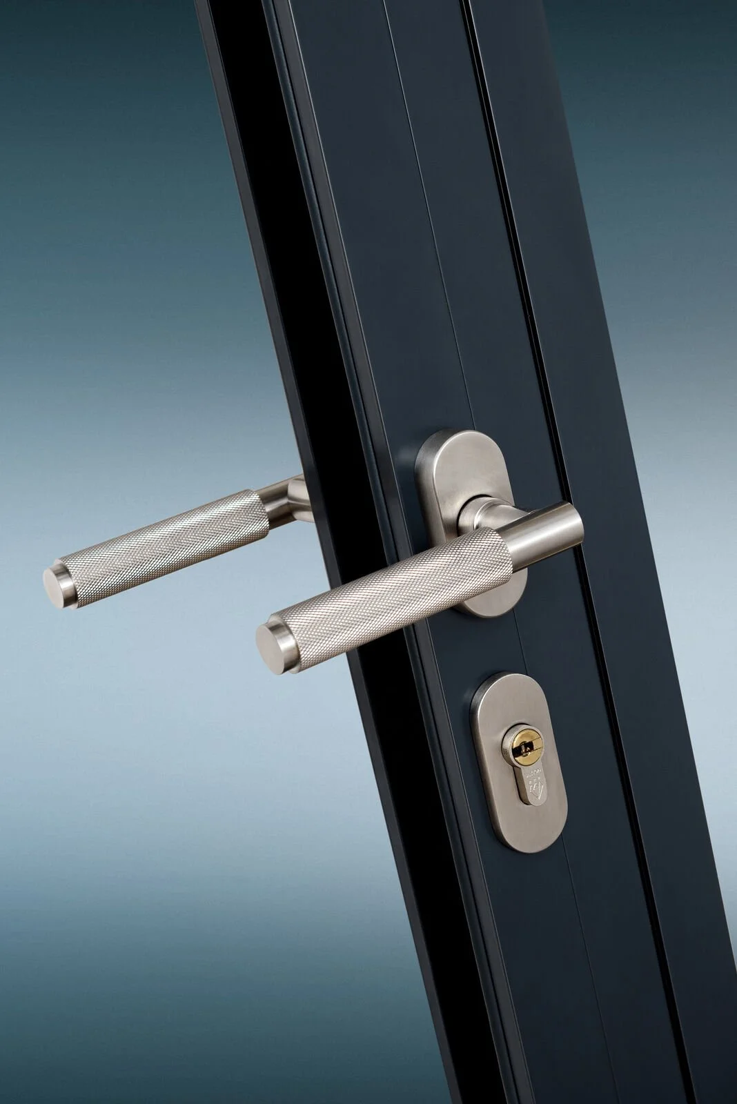 Close-up of a modern door lock and handle on a dark door with a blue background.