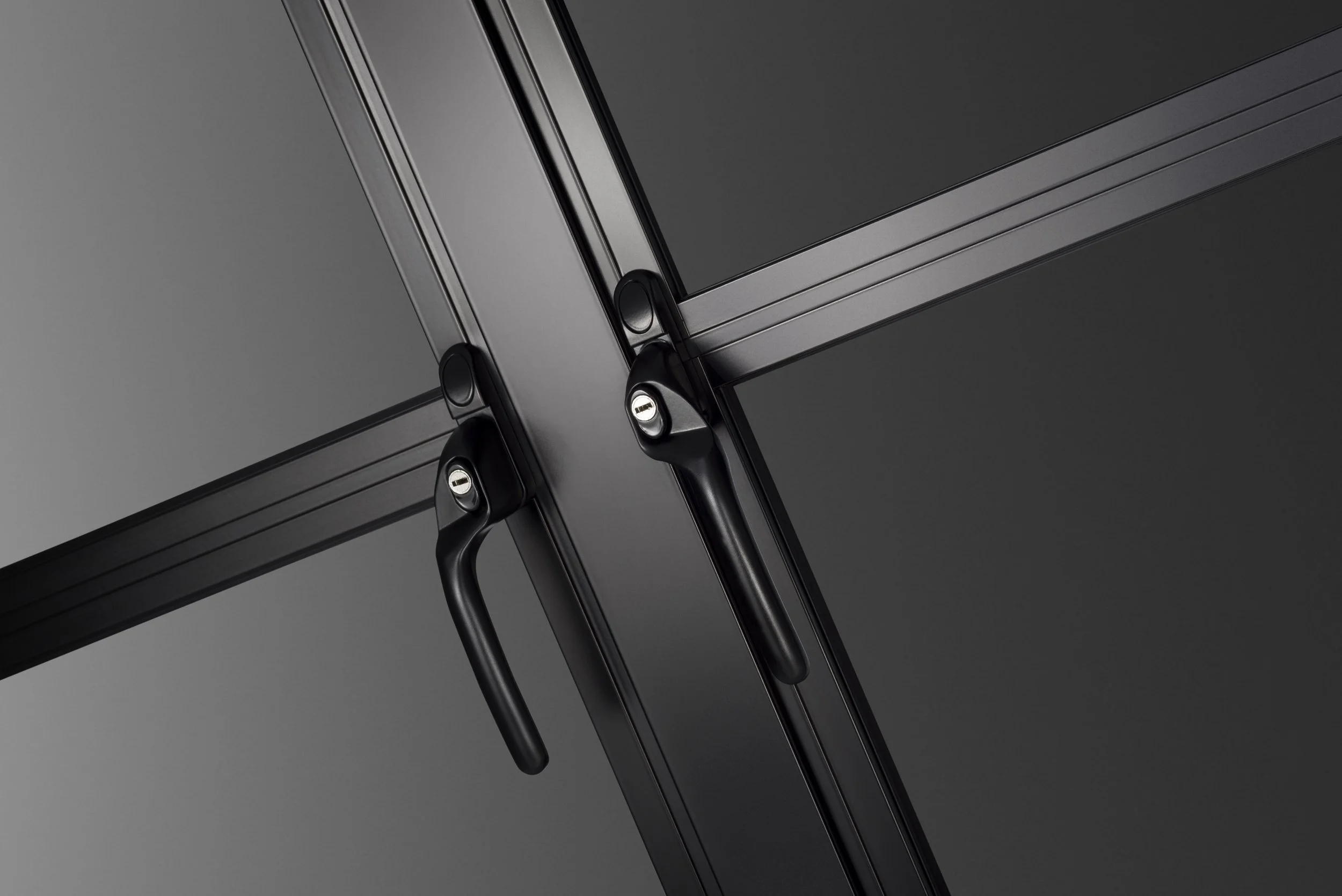 Close-up of black metal window frames with handles and locks against a dark background.