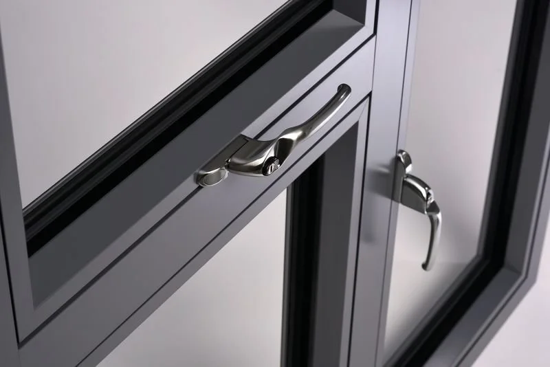 Close-up of an anthracite grey aluminium window with a handle and a lock.