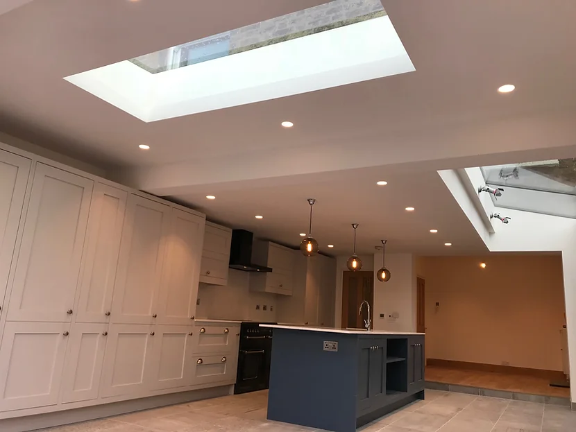 Modern kitchen with white cabinets, a central blue island, pendant lights, and skylights in the ceiling.