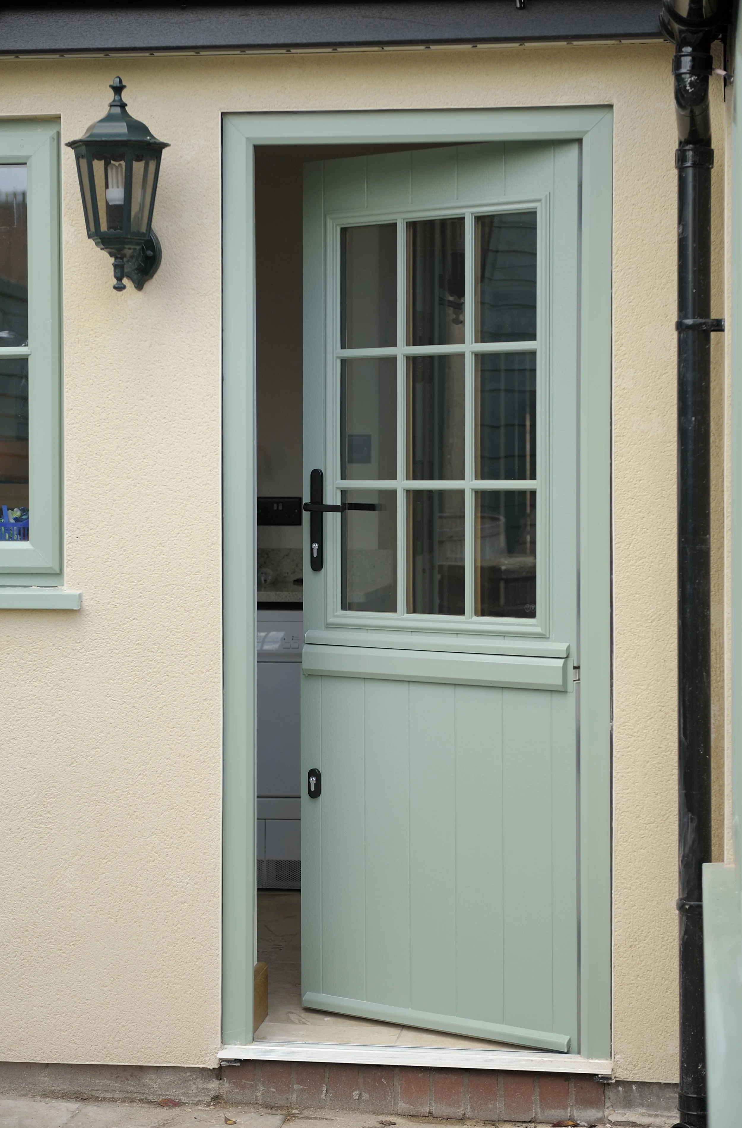 Open green mesh door with glass window panels, leading into a laundry room.