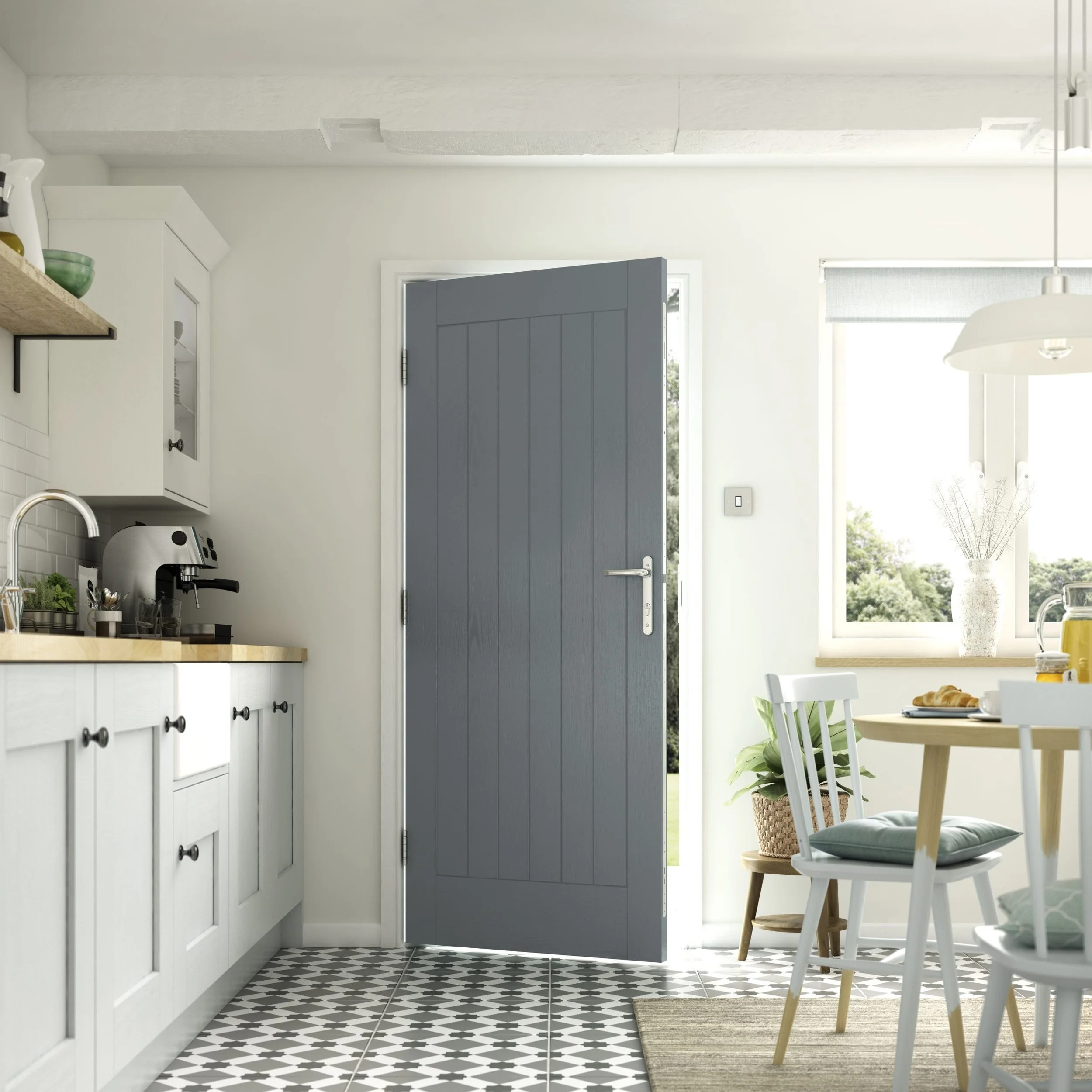Interior view of a bright kitchen with a partially open gray front door, white cabinetry, a window with a view of greenery, a dining table with chairs, and patterned floor tiles.