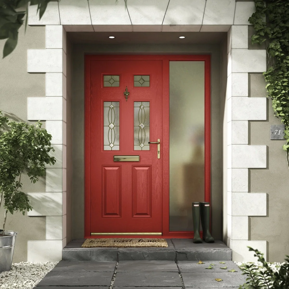 Red front door with decorative glass panels and a mail slot, flanked by a frosted glass sidelight on the right, with black rain boots placed outside on the right, and surrounded by a cream-colored wall with white stone detailing, a potted plant on th