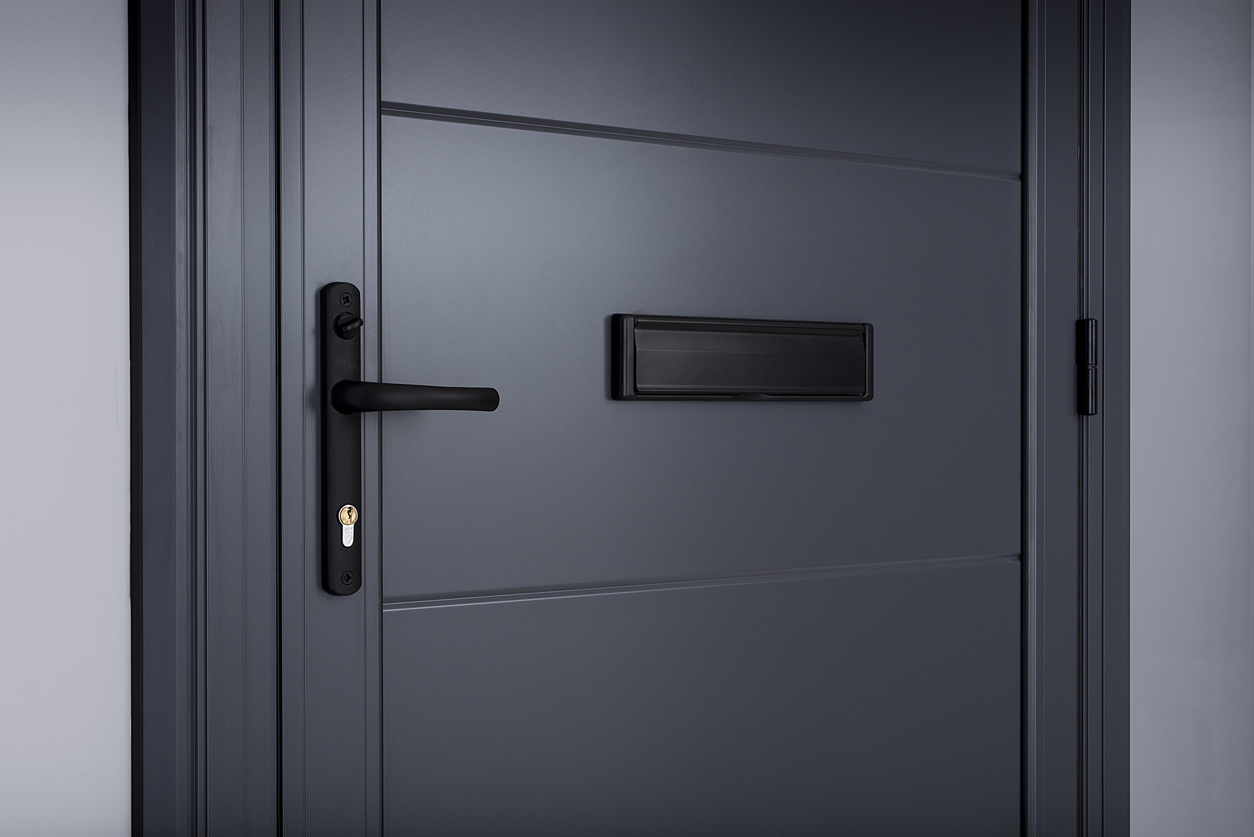 Close-up of a modern dark gray front door with a black handle, lock, and mail slot.