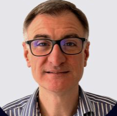 A man with short brown hair, glasses, and a striped shirt smiling at the camera.