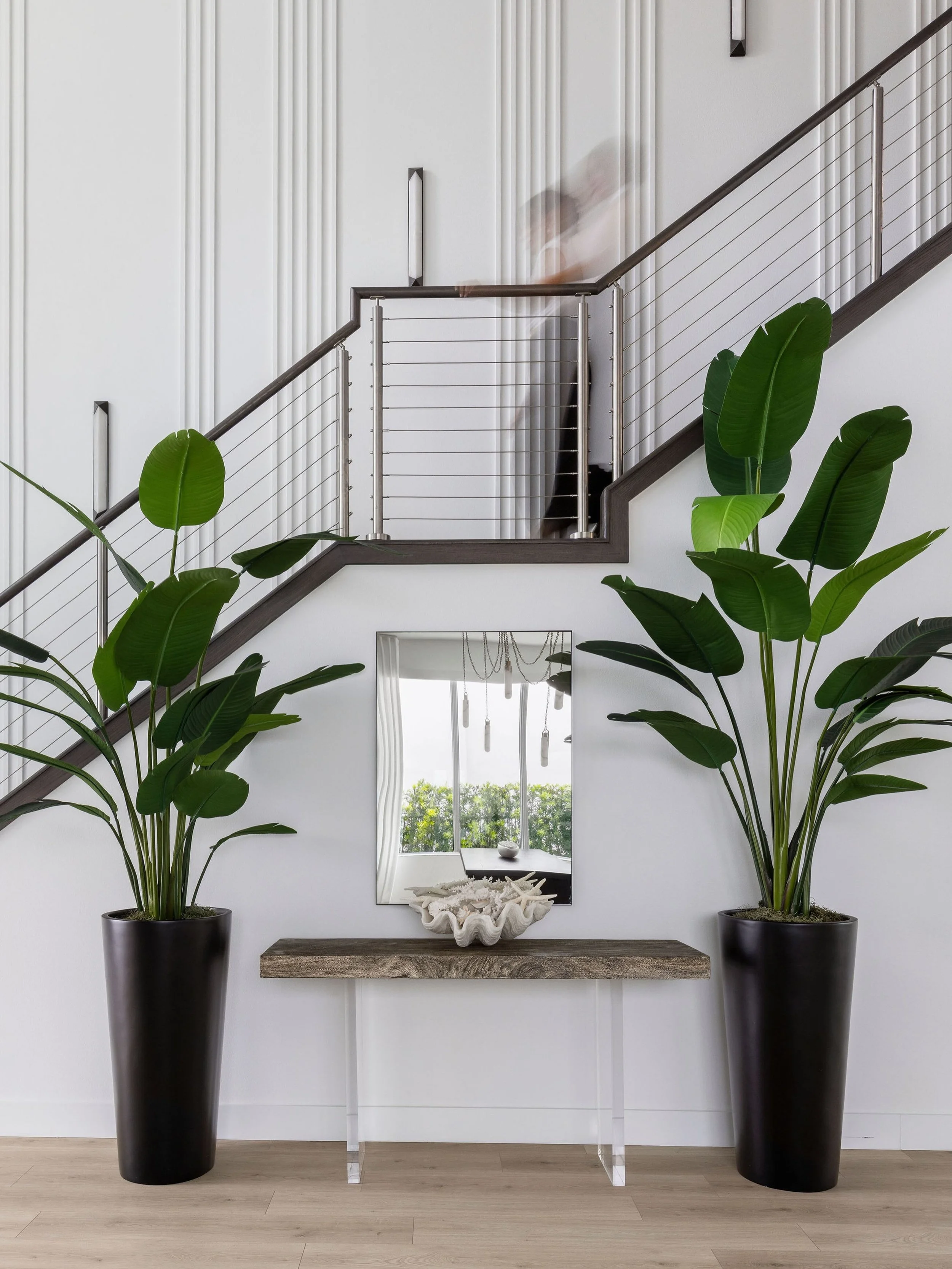The secret to a great double-height entry? Give the eye somewhere to land at every level. Millwork for texture, alabaster sconces for warmth, and a coastal-modern console moment grounding it all in the everyday. Height makes a statement &mdash; but i