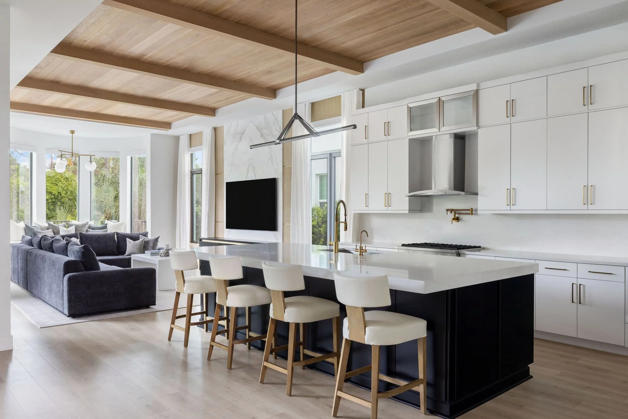 Modern open concept kitchen and living room in Palm Beach Gardens FL with white oak ceiling, white cabinetry, brass hardware, by Interiors by Casa Mia.