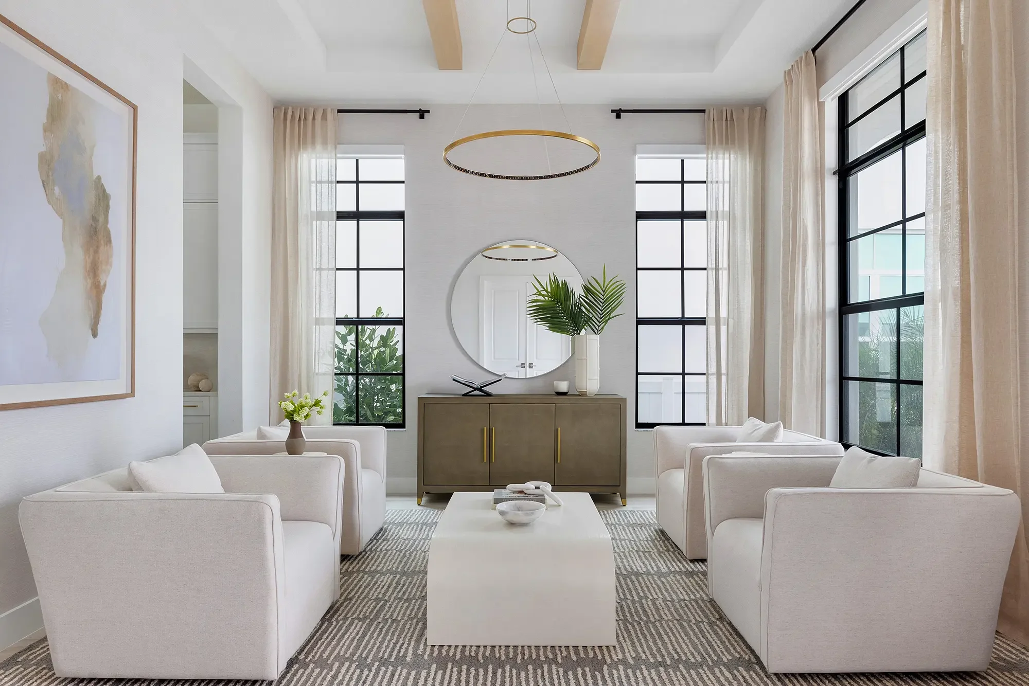 Luxury sitting room in Palm Beach Gardens FL with cream chairs, brass ring chandelier, black steel windows, and coastal sideboard by Interiors by Casa Mia.