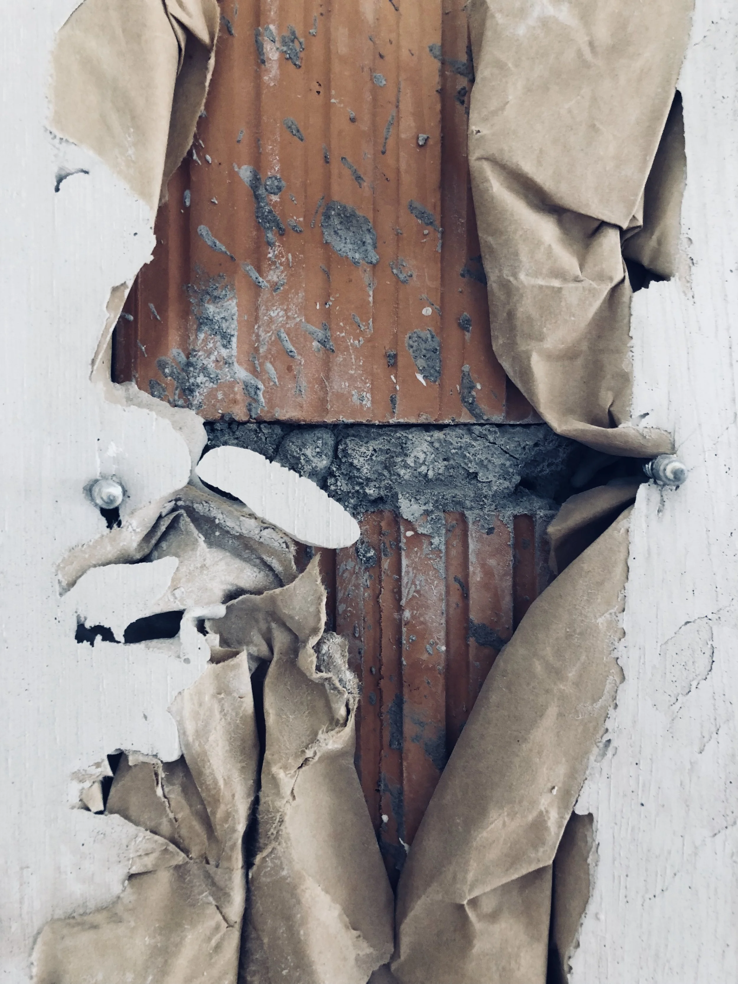 A broken wall opening showing exposed wood, insulation, and debris behind drywall.