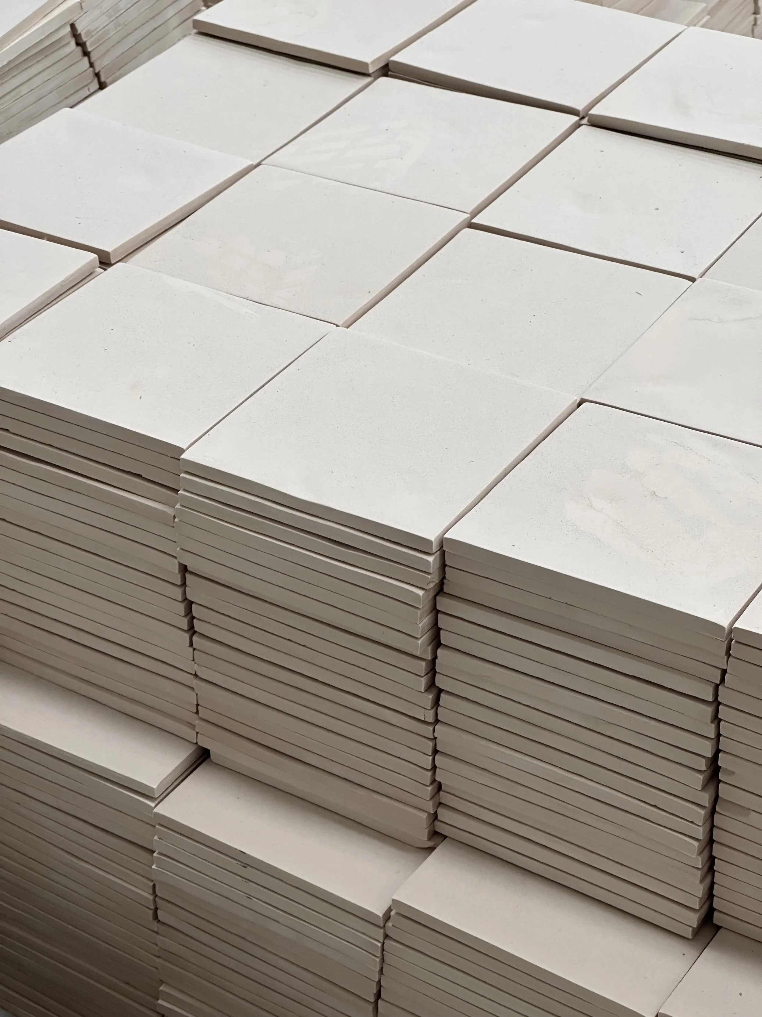 Stacks of white ceramic tiles arranged in a pyramid shape.