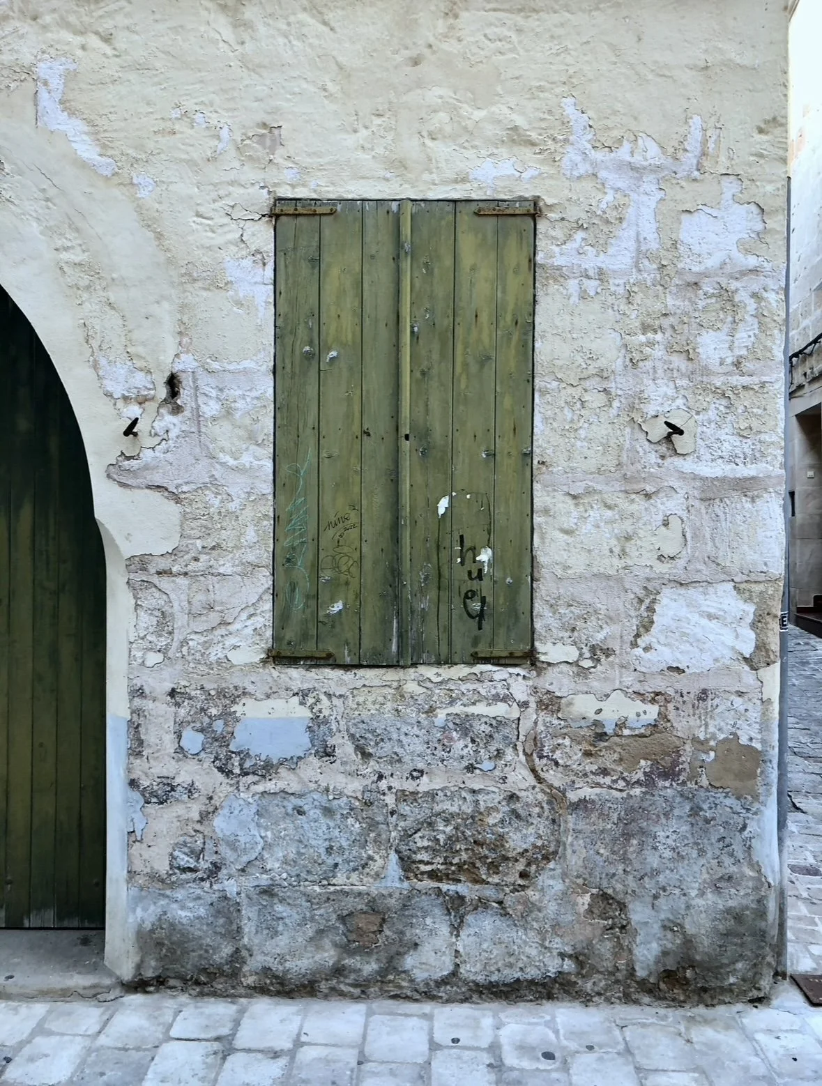 Facade of a Mediterranean stone house with green shutters.