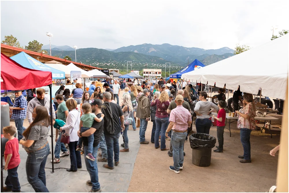 Pioneer Rodeo families visiting vendors with Colorado mountains behind them