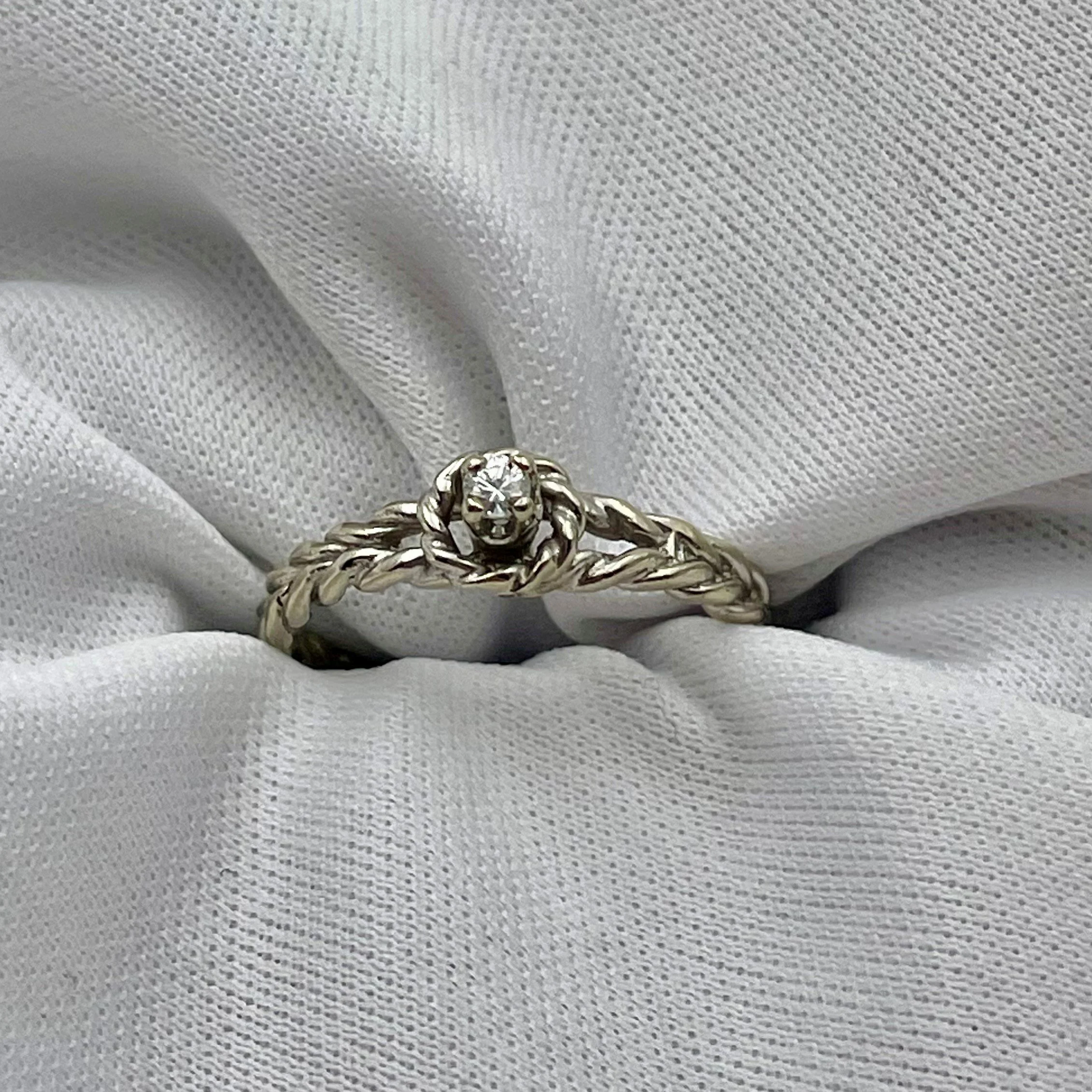 top down view of white gold rope patterned diamond promise ring with white fabric background