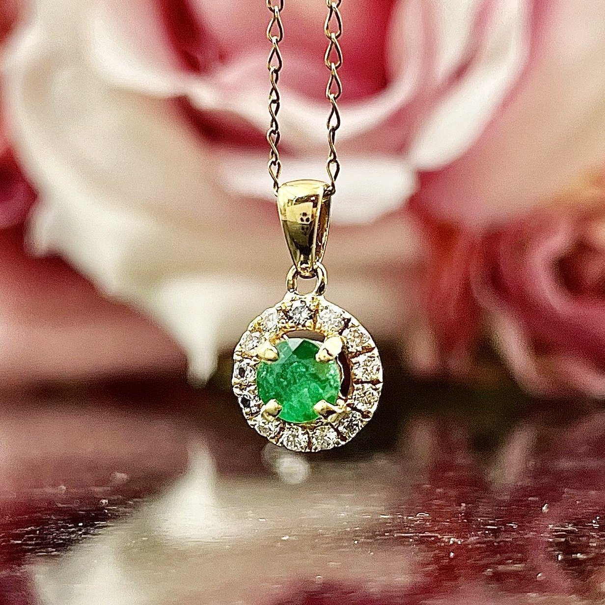 close up in front of flowers 18k Yellow Gold Emerald With Diamond Halo Pendant