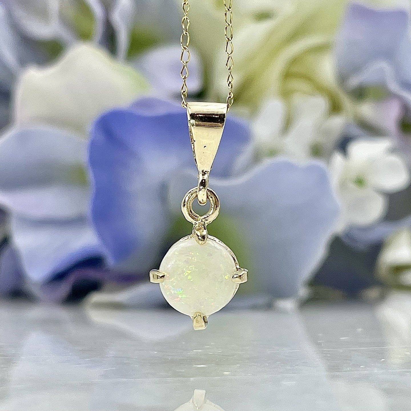 close up in front of flowers 14k Yellow Gold Pear Cut Opal With Diamond Accent Drop Pendant