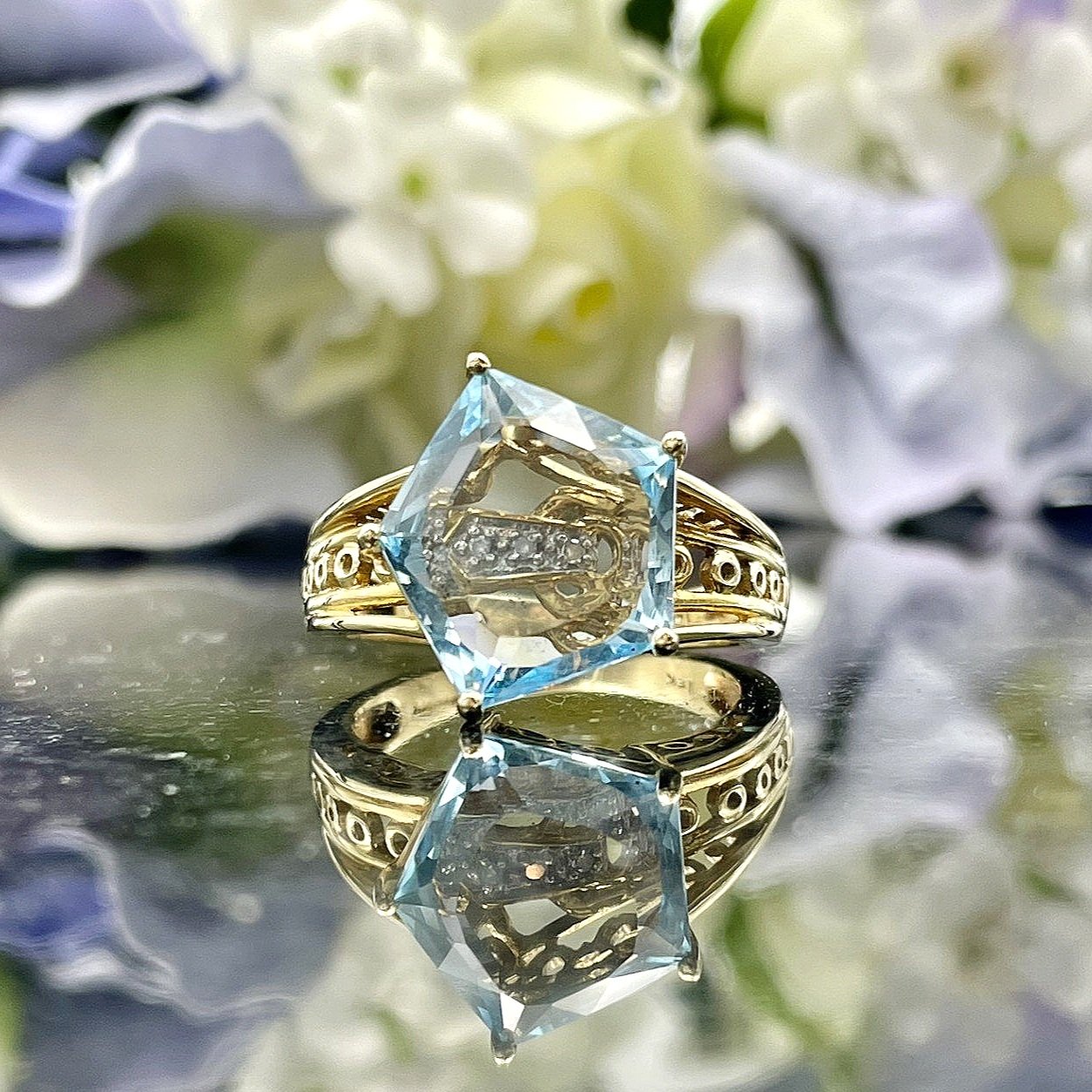 close up in front of flowers Fancy Pentagon Cut Blue Topaz With Diamond Accent Ladies Ring 14k Yellow Gold