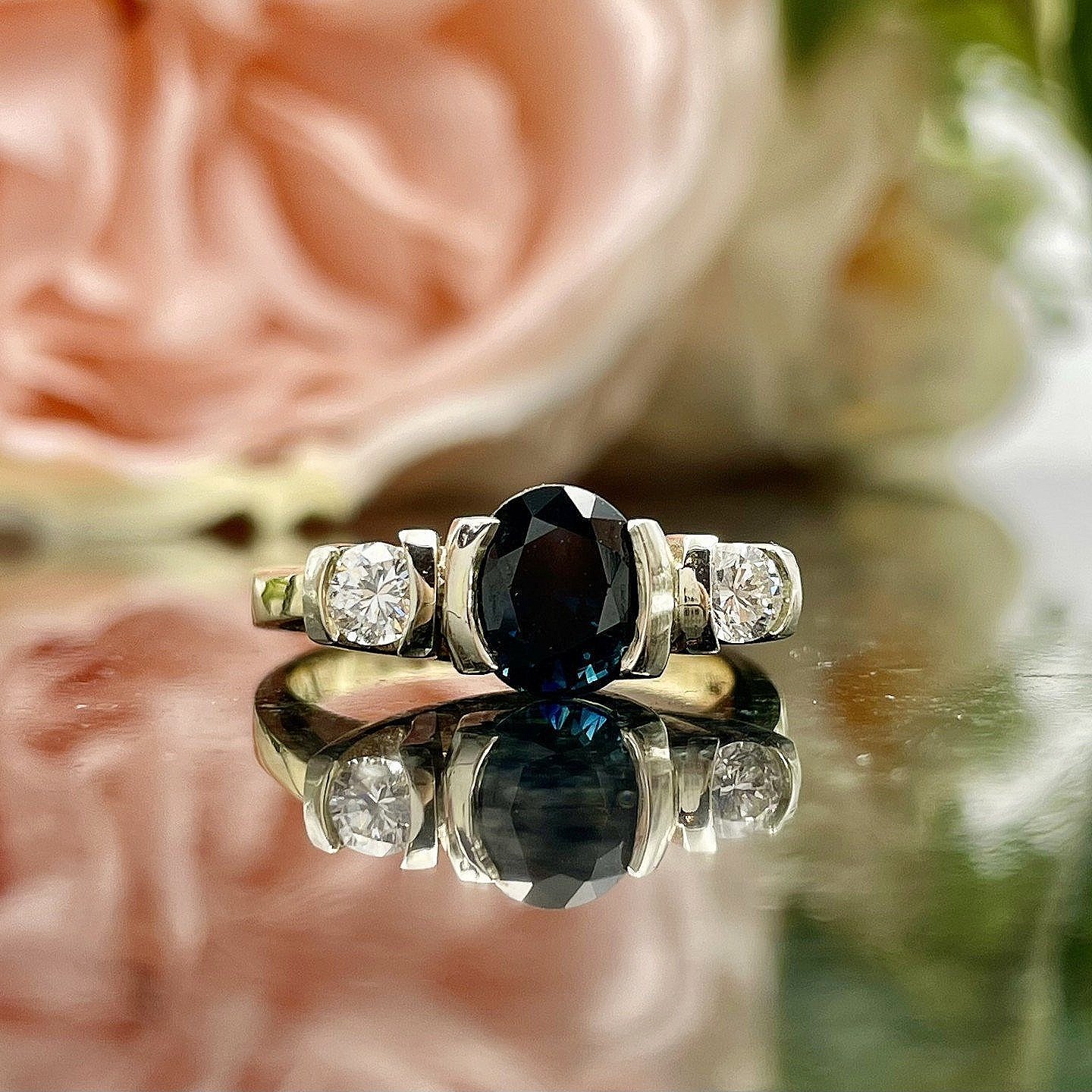 close up in front of flowers 1.79ct Oval Sapphire With Diamonds Three Stone 14k Two Tone Yellow And White Gold Ring