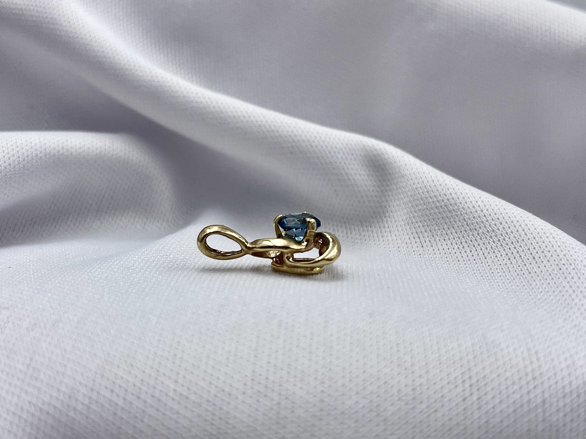 Celtic Inspired 14k Yellow Gold With Blue Topaz Pendant side view in front of white cloth