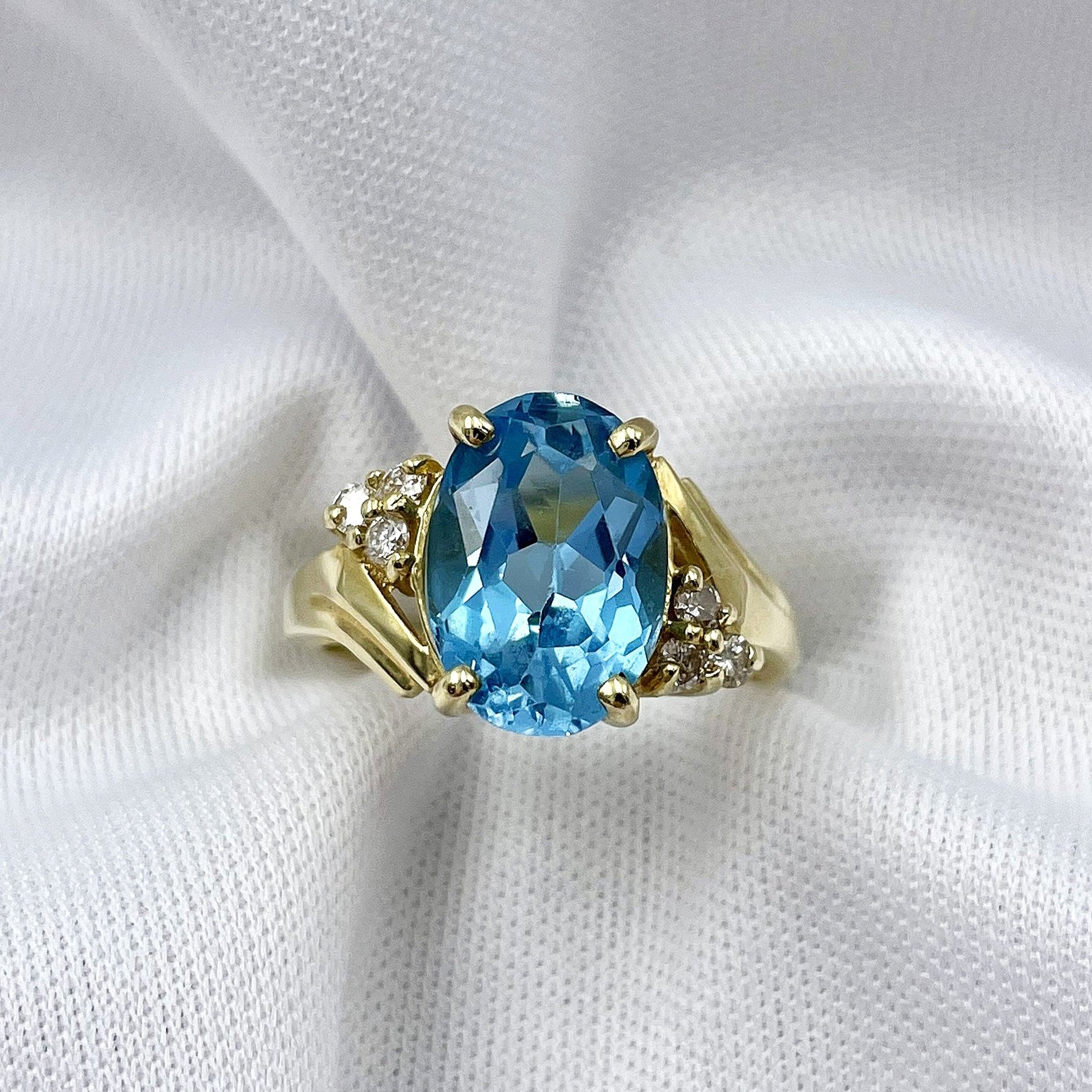 top down close up white background 14k Yellow Gold Oval Cut Blue Topaz With Diamond Accents Ladies Bypass Ring