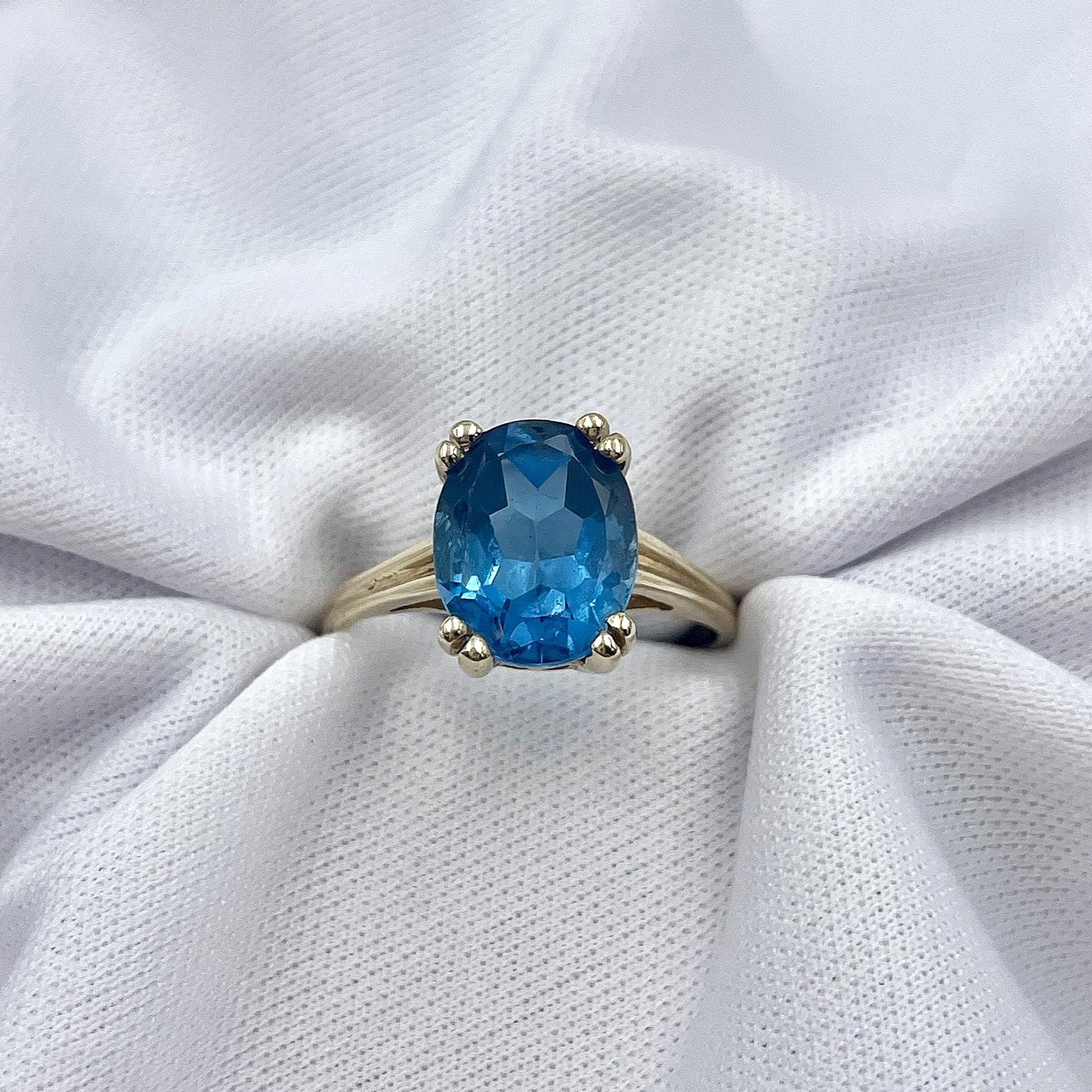 top down white background Oval Cut Blue Topaz Solitaire Ladies Ring 14k Yellow Gold
