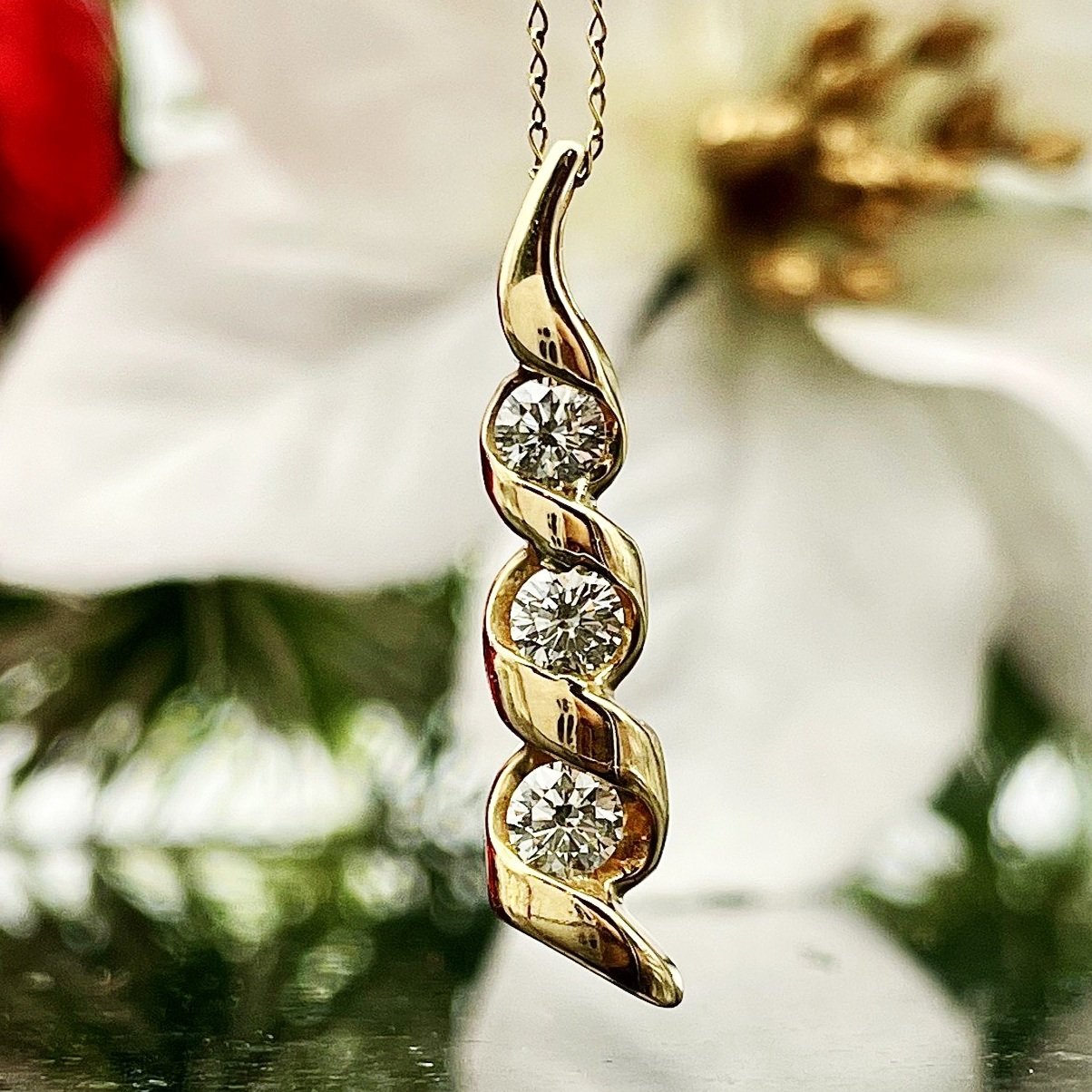 close up in front of florals 1/2ctw A+ Quality Three Stone Diamond Twist Pendant 14k Yellow Gold