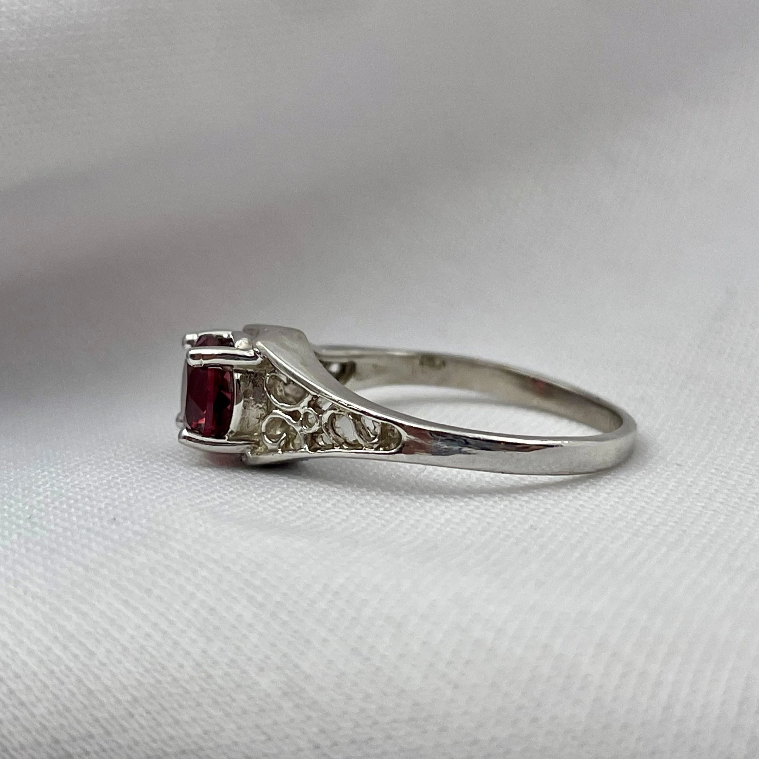 side view of 14k White Gold 6mm Round Garnet Ladies Rings With Filigree Shoulders in front of white background