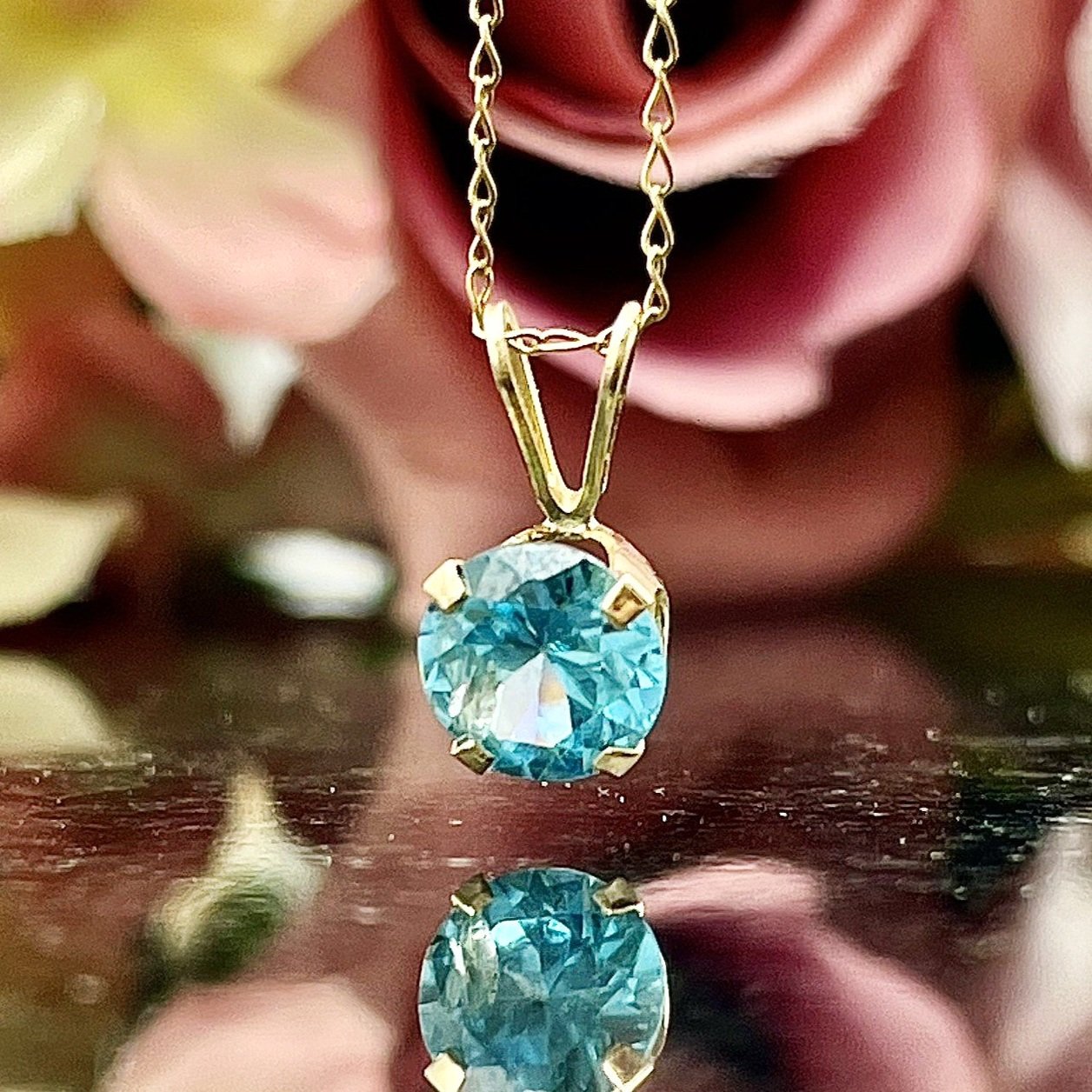 close up in front of flowers 1.11ct Solitaire Blue Zircon Pendant 14k yellow gold