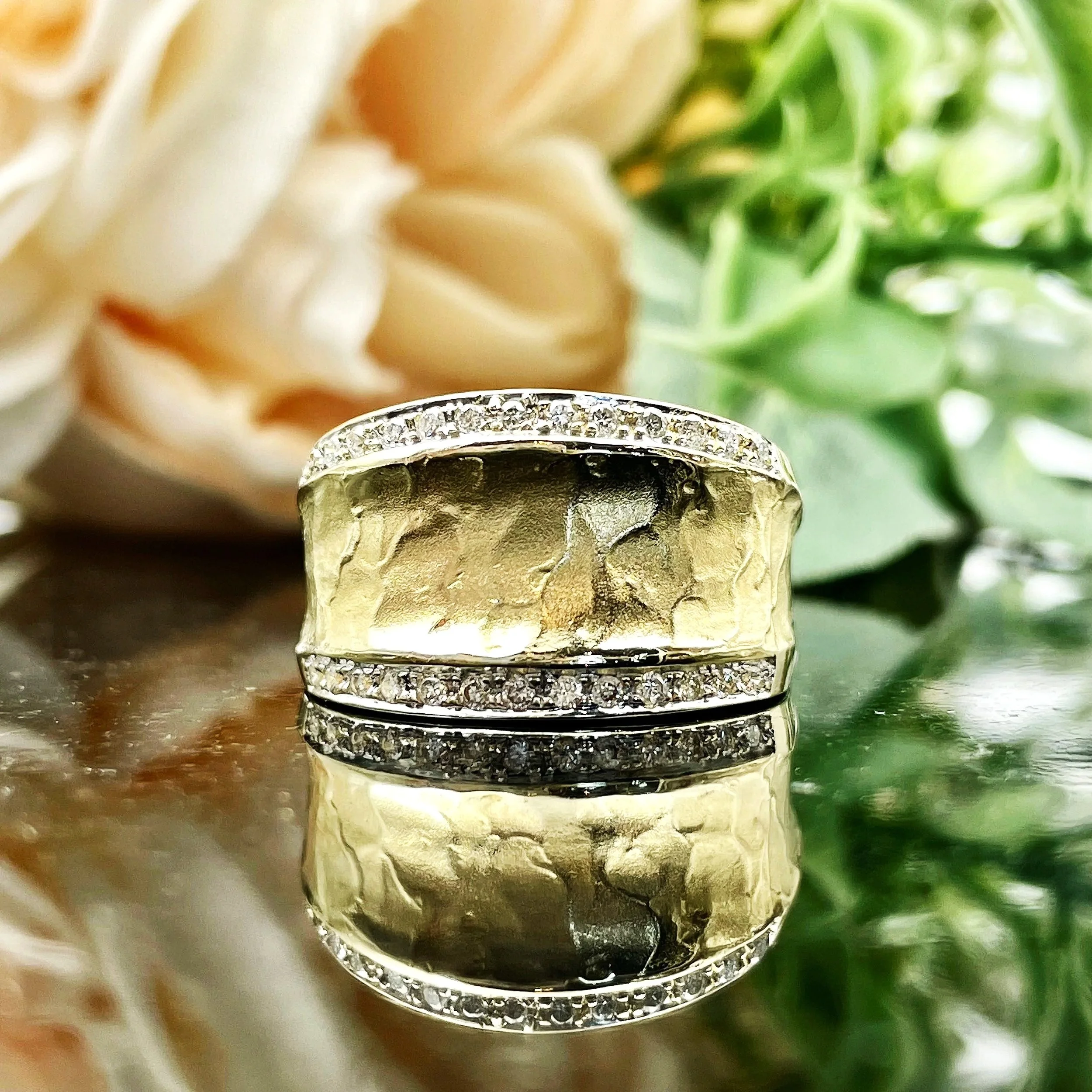 front view of 14k Yellow Gold .15ctw Diamond Accents Fancy Wide Fashion Band Unique Ladies Ring in front of florals