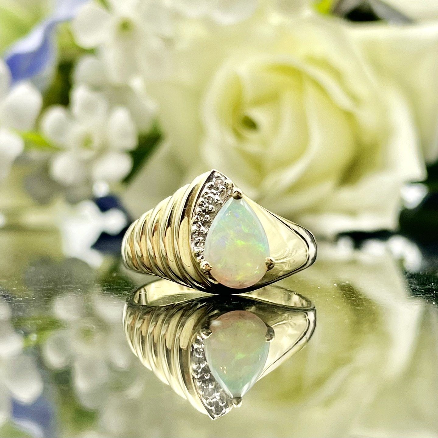 close up in front of flowers 14k Yellow Gold Pear Cut Opal With Diamond Accents Ladies Ring