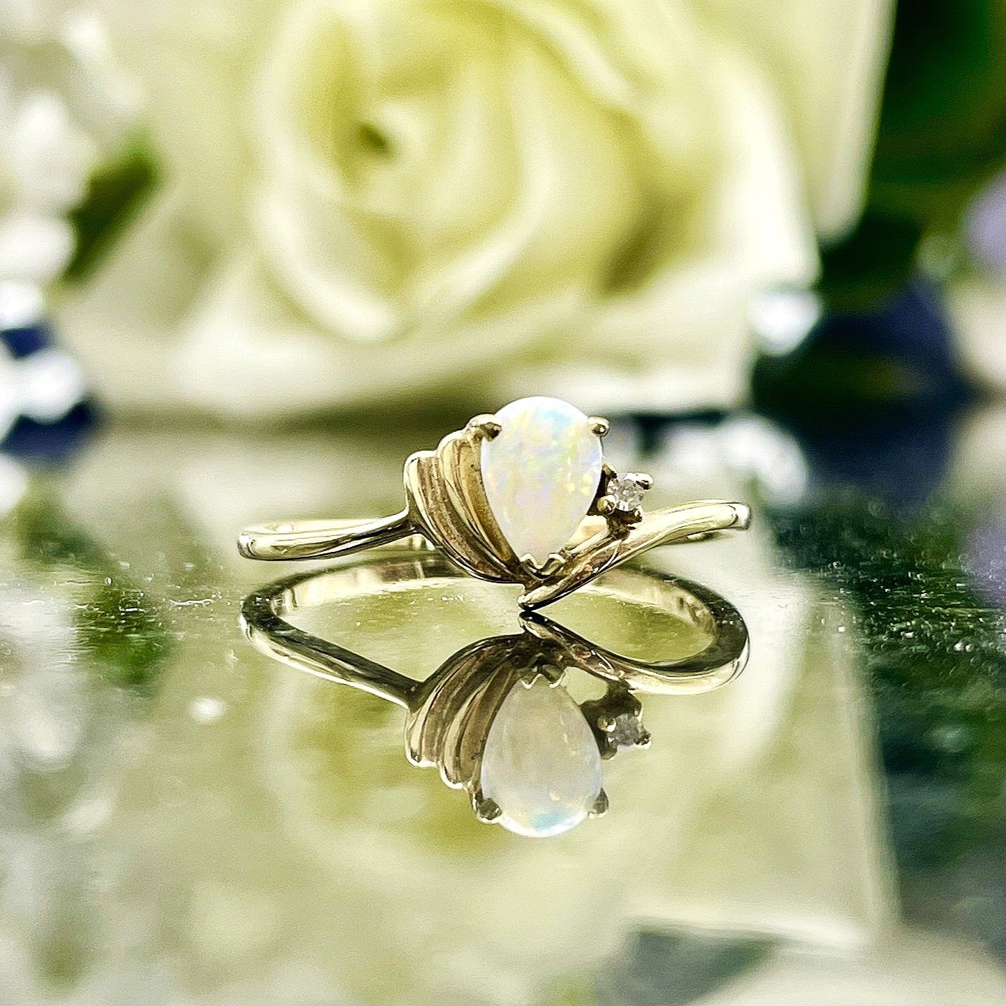 close up in front of flowers 10k Yellow Gold Pear Cut Opal With Diamond Accent Ladies Ring