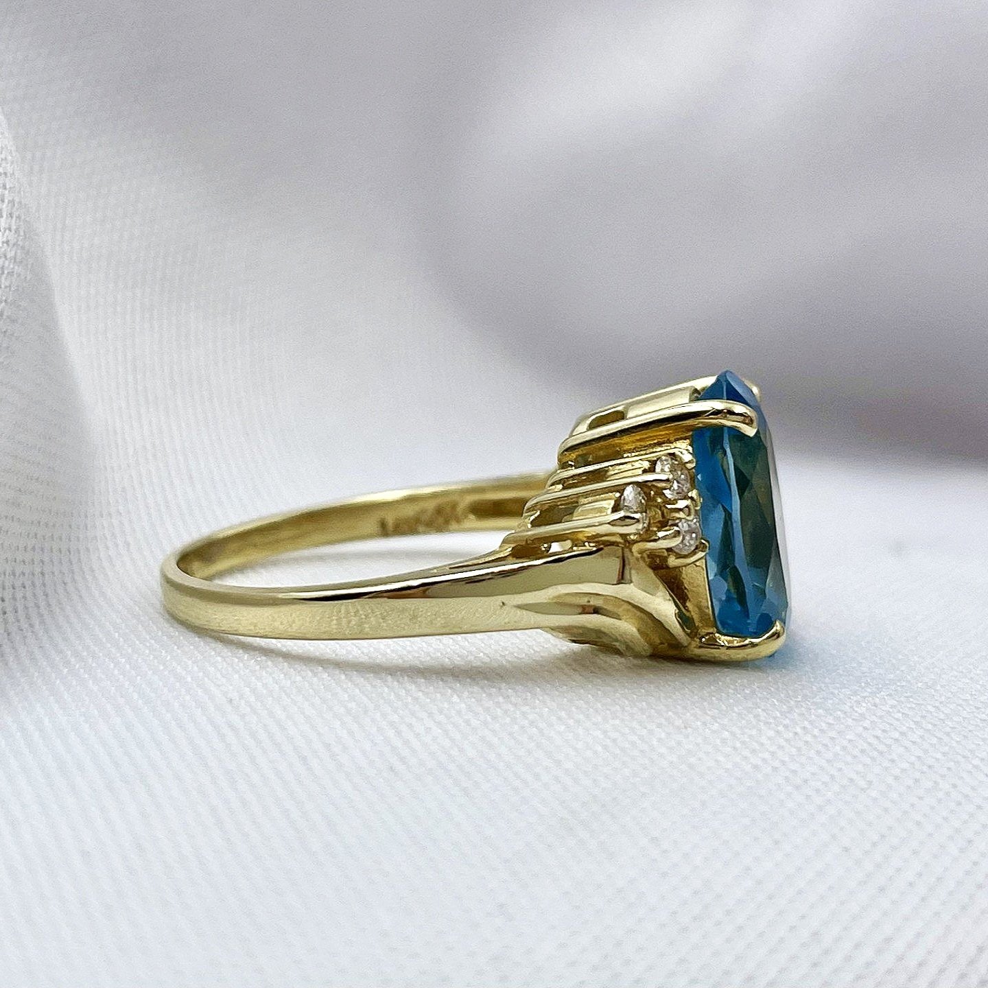 side view white background 14k Yellow Gold Oval Cut Blue Topaz With Diamond Accents Ladies Bypass Ring