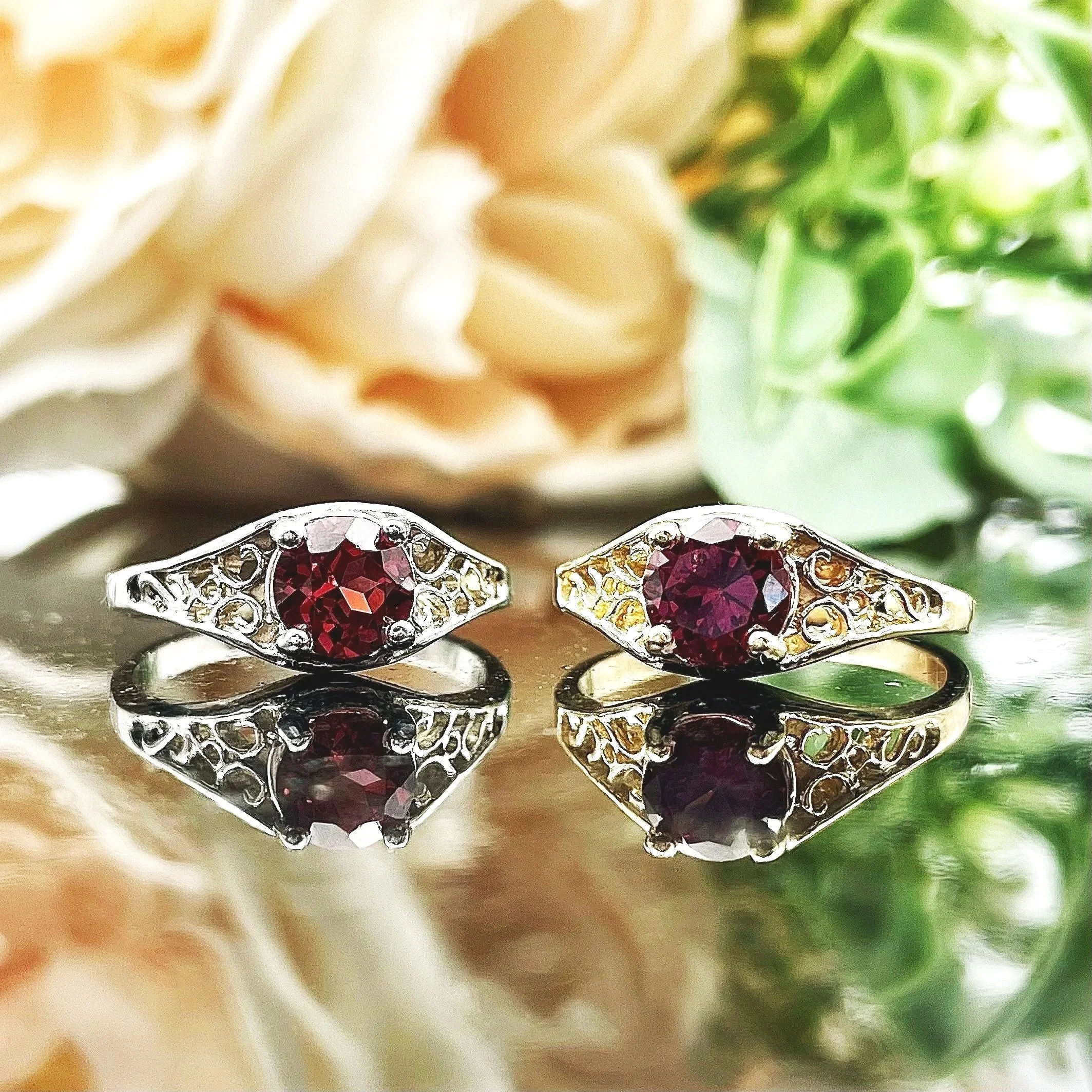 side by side of 14k Yellow or White Gold 6mm Round Garnet Ladies Rings With Filigree Shoulders in front of florals