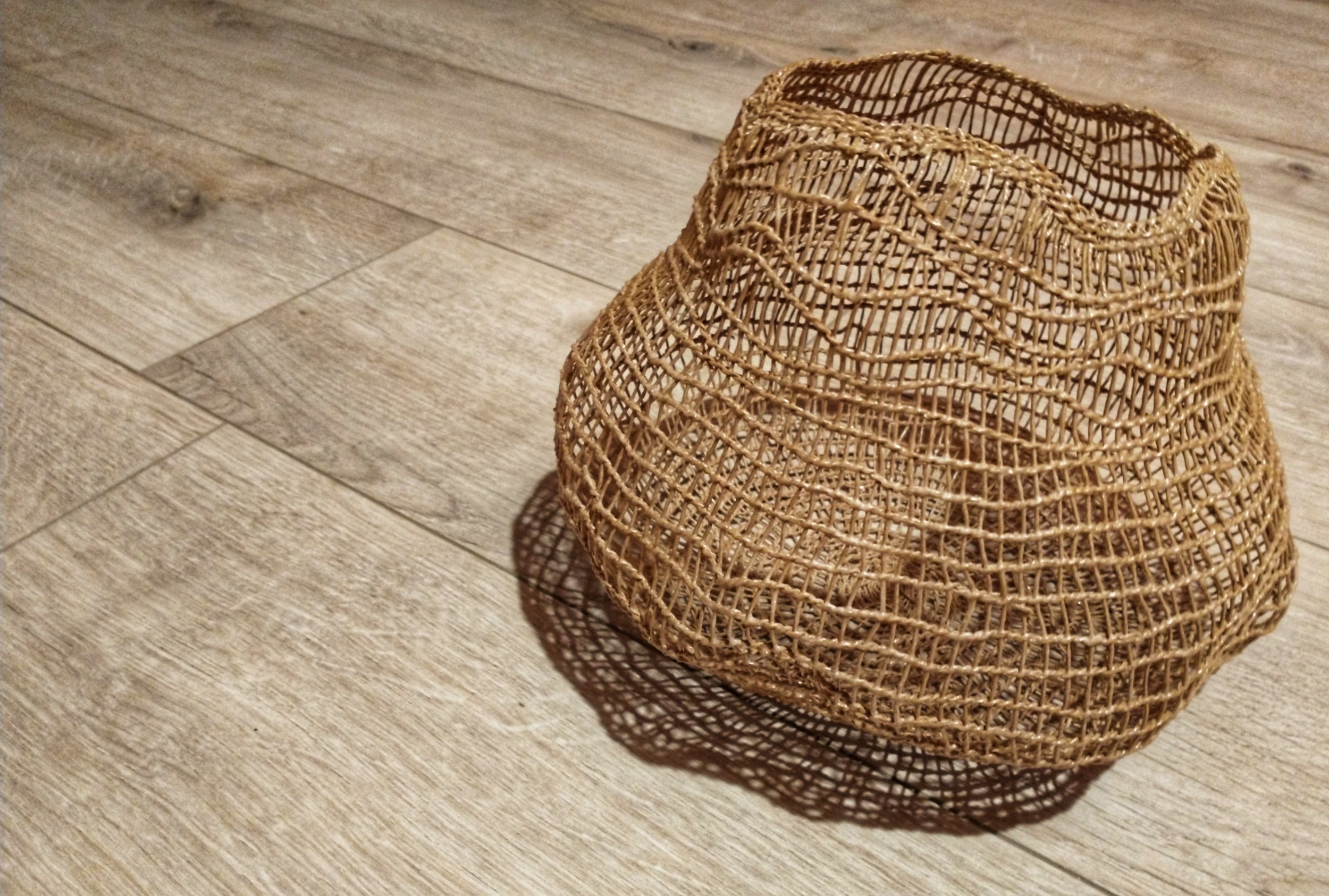 this is an image of a tan coloured open with vessel with a wavy rim made using paper string