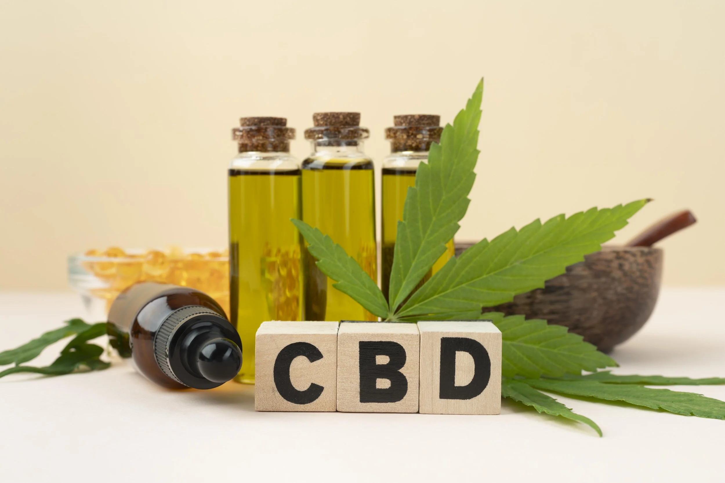 cannabis products on table including capsules, tincture, vials of oil, cannabis leaf and blocks displaying CBD