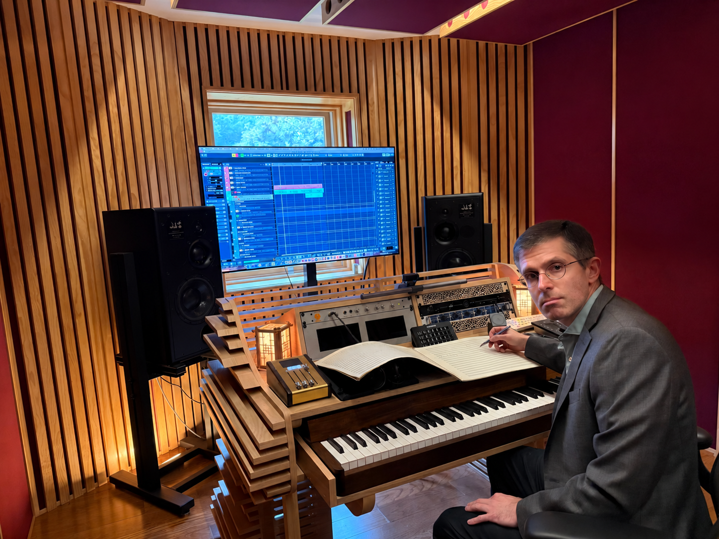 Ron Artinian composing at his piano, with an open orchestral score in his studio.
