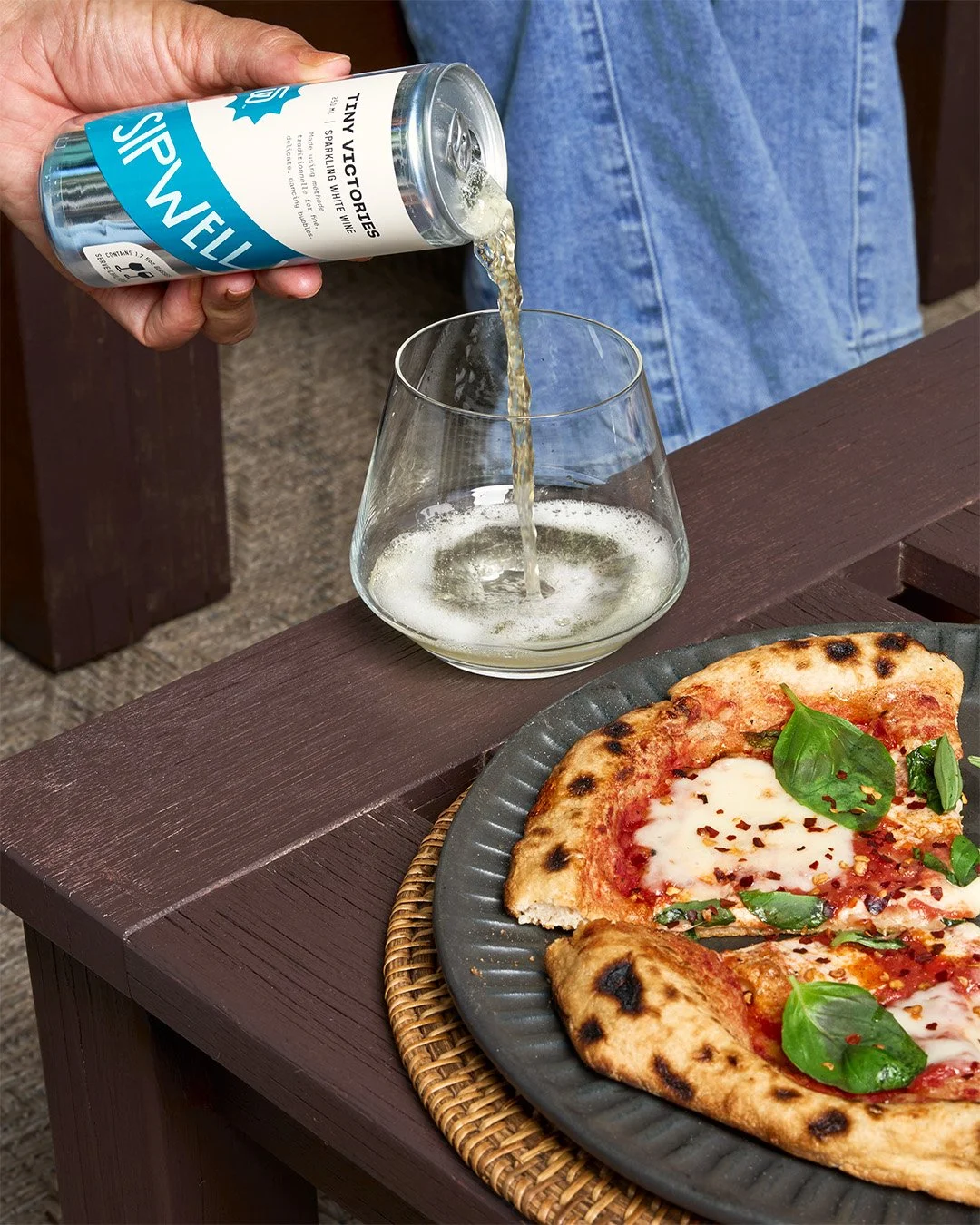 Hand pouring Sipwell wine beverage into glass over fresh pizza, lifestyle food and beverage photography by Golden Joy Photography in Los Angeles