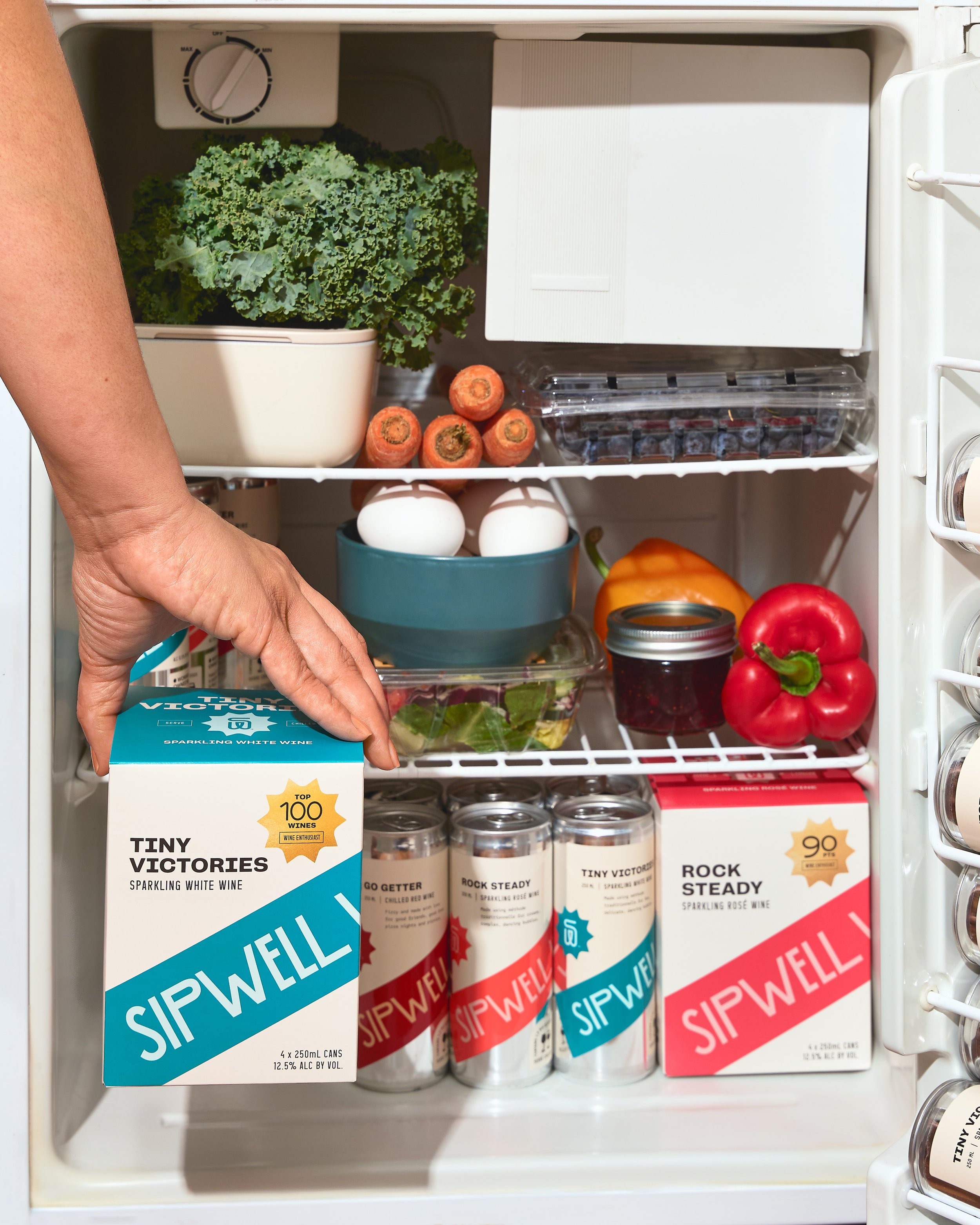 Hand reaching into refrigerator stocked with SipWell wine beverages, lifestyle beverage photography by Golden Joy Photography in Los Angeles