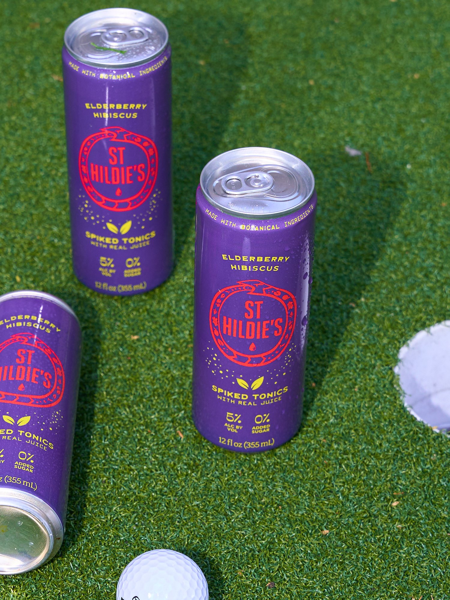 Spiked tonic cans arranged on green turf in an outdoor setting