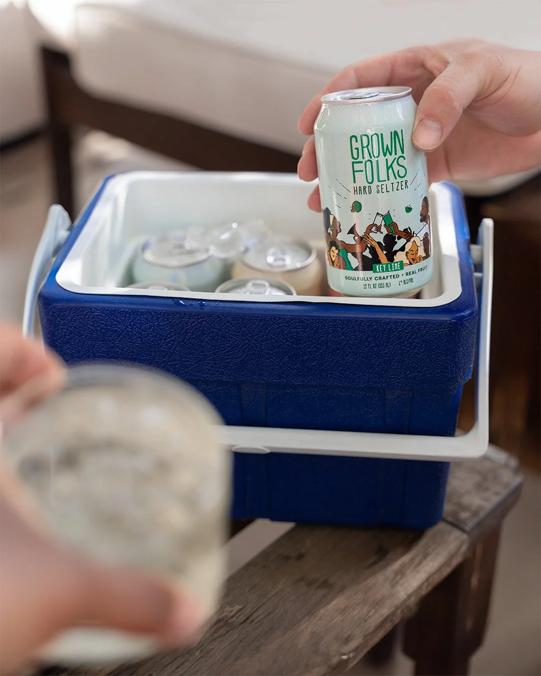 Hand holding Grown Folks Seltzer beverage can over blue cooler with ice, lifestyle beverage photography by Golden Joy Photography in Los Angeles