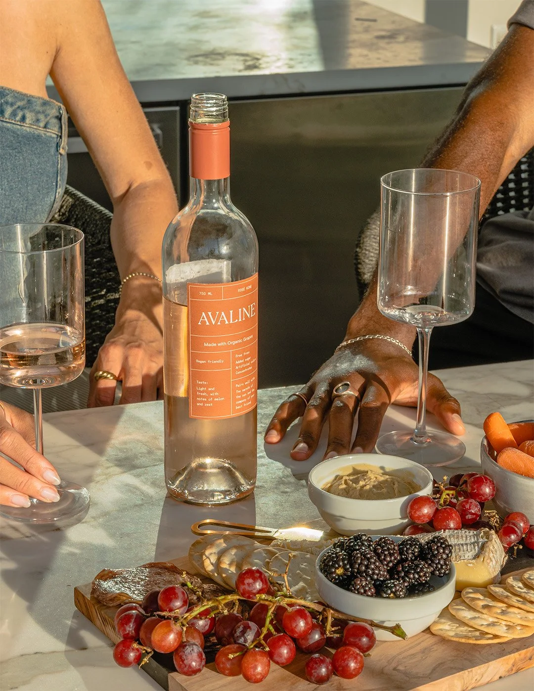 Hands holding glass of Avaline wine over charcuterie board with appetizers, lifestyle beverage photography by Golden Joy Photography in Los Angeles