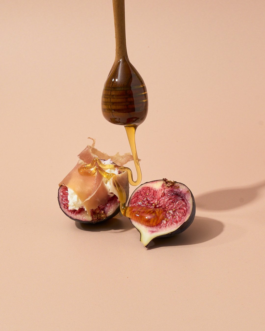 Honey drizzling onto fresh figs from wooden dipper, product food photography by Golden Joy Photography in Los Angeles