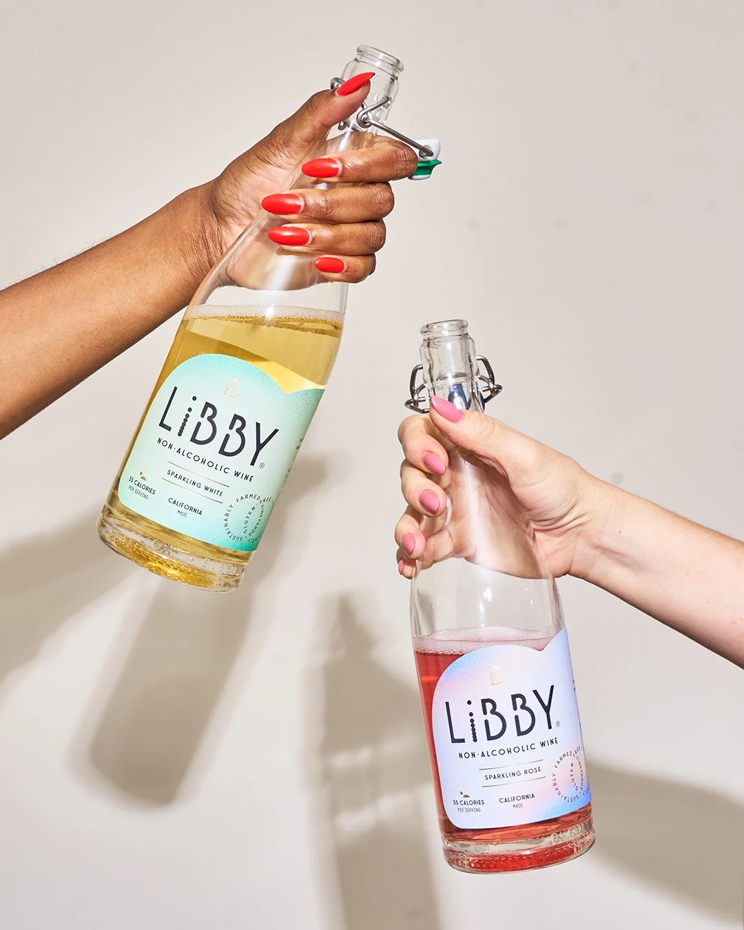 Two people toasting with LiBBY non-alcoholic beverage bottles, lifestyle beverage photography by Golden Joy Photography in Los Angeles