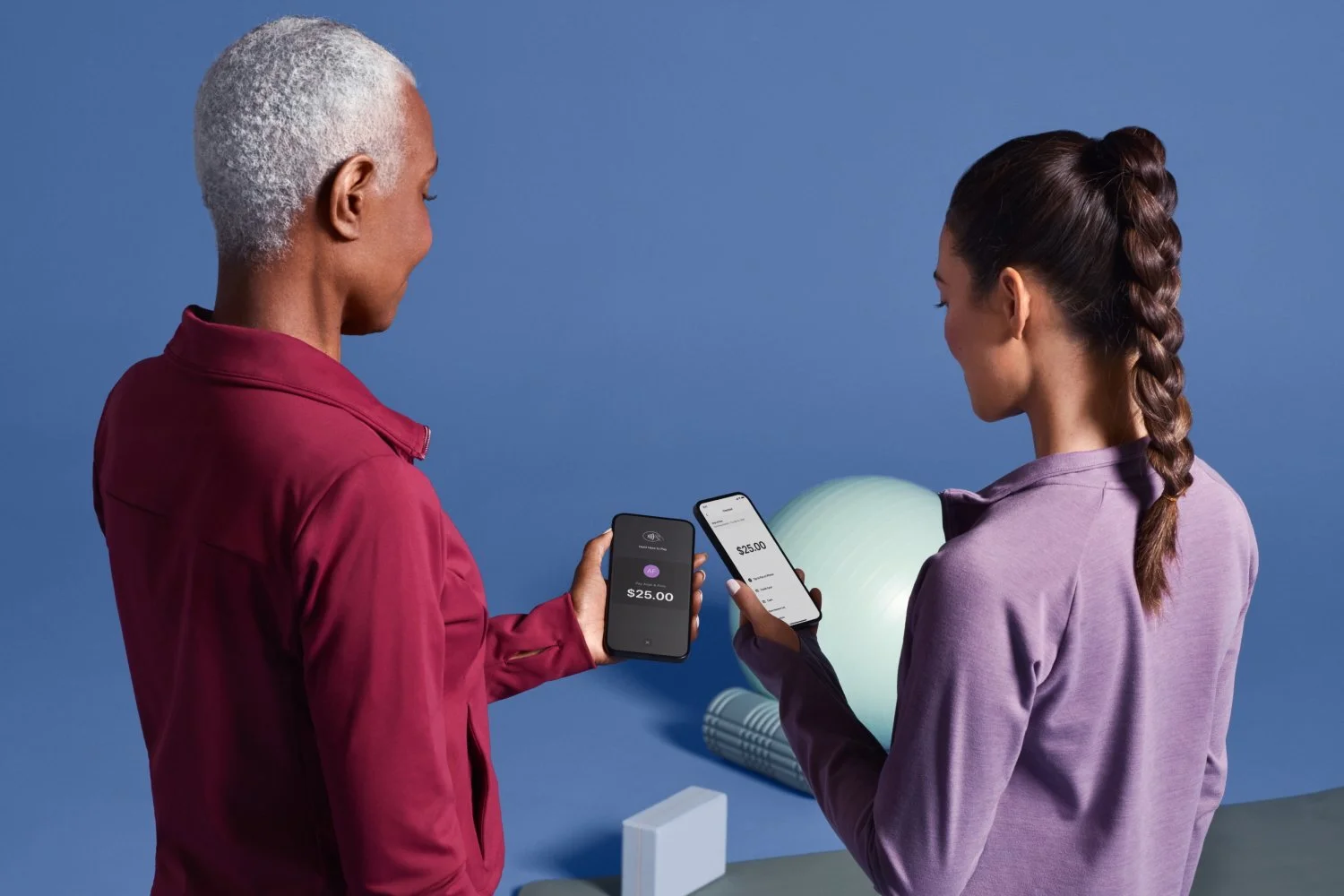Fitness instructor and client using mobile phones to complete payment after a workout session