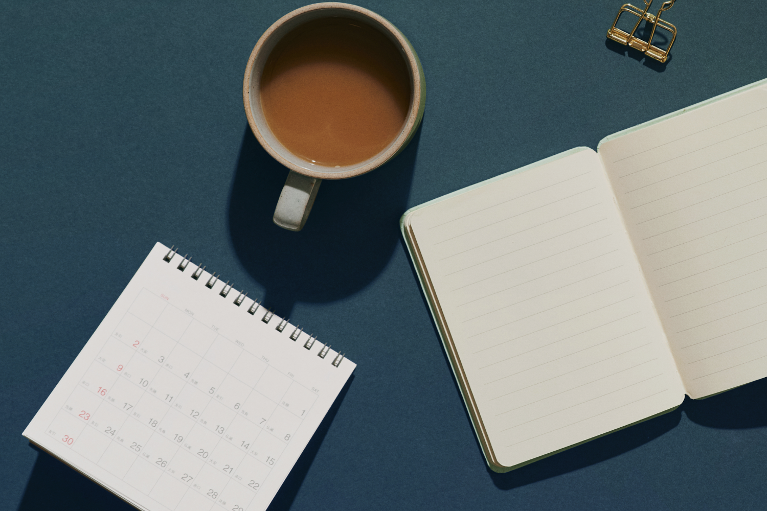 Calendar and notebook next to cup of coffee