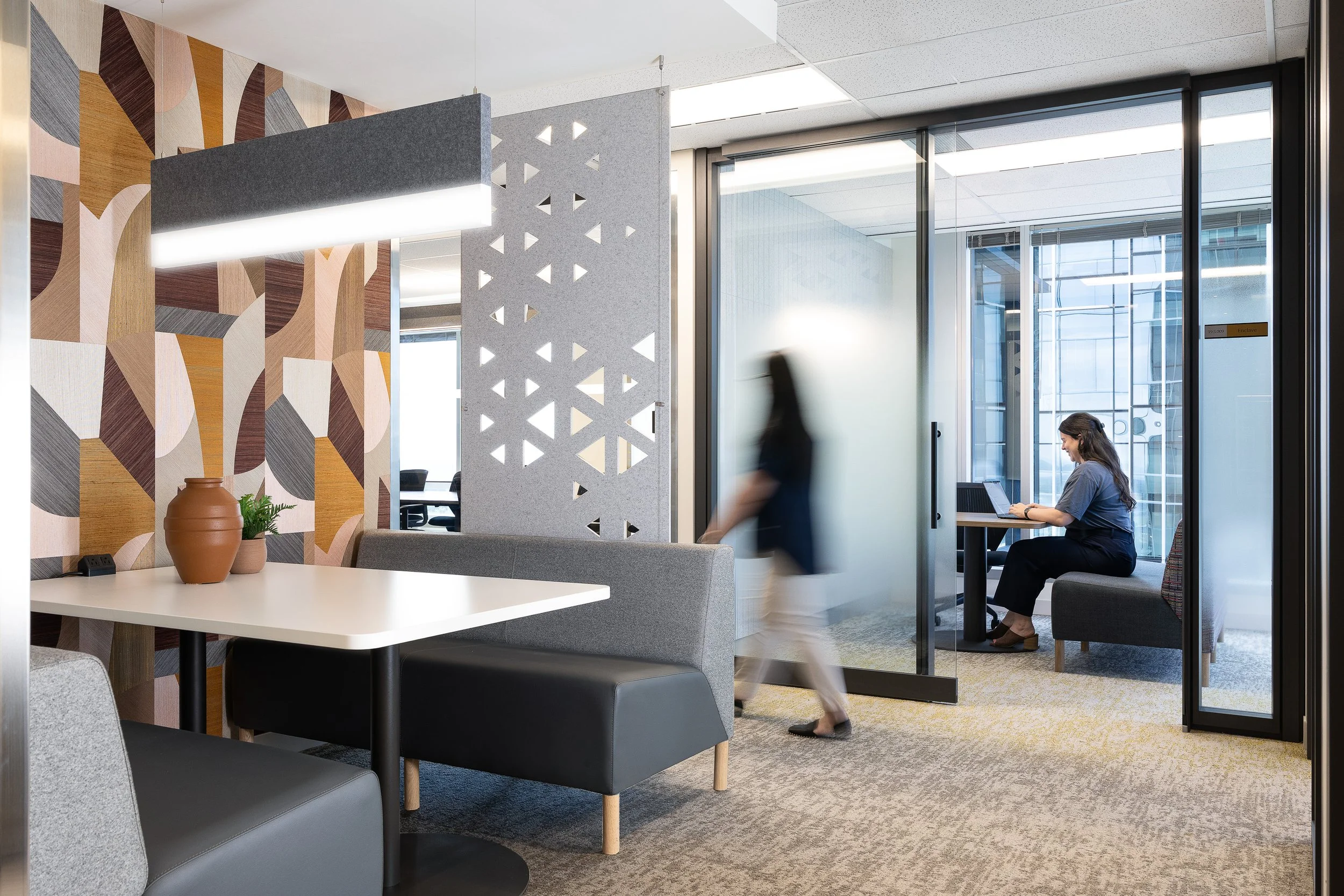 Small meeting room in the Sun Life office with soft seating, acoustic wall panels, and integrated linear wall lighting.