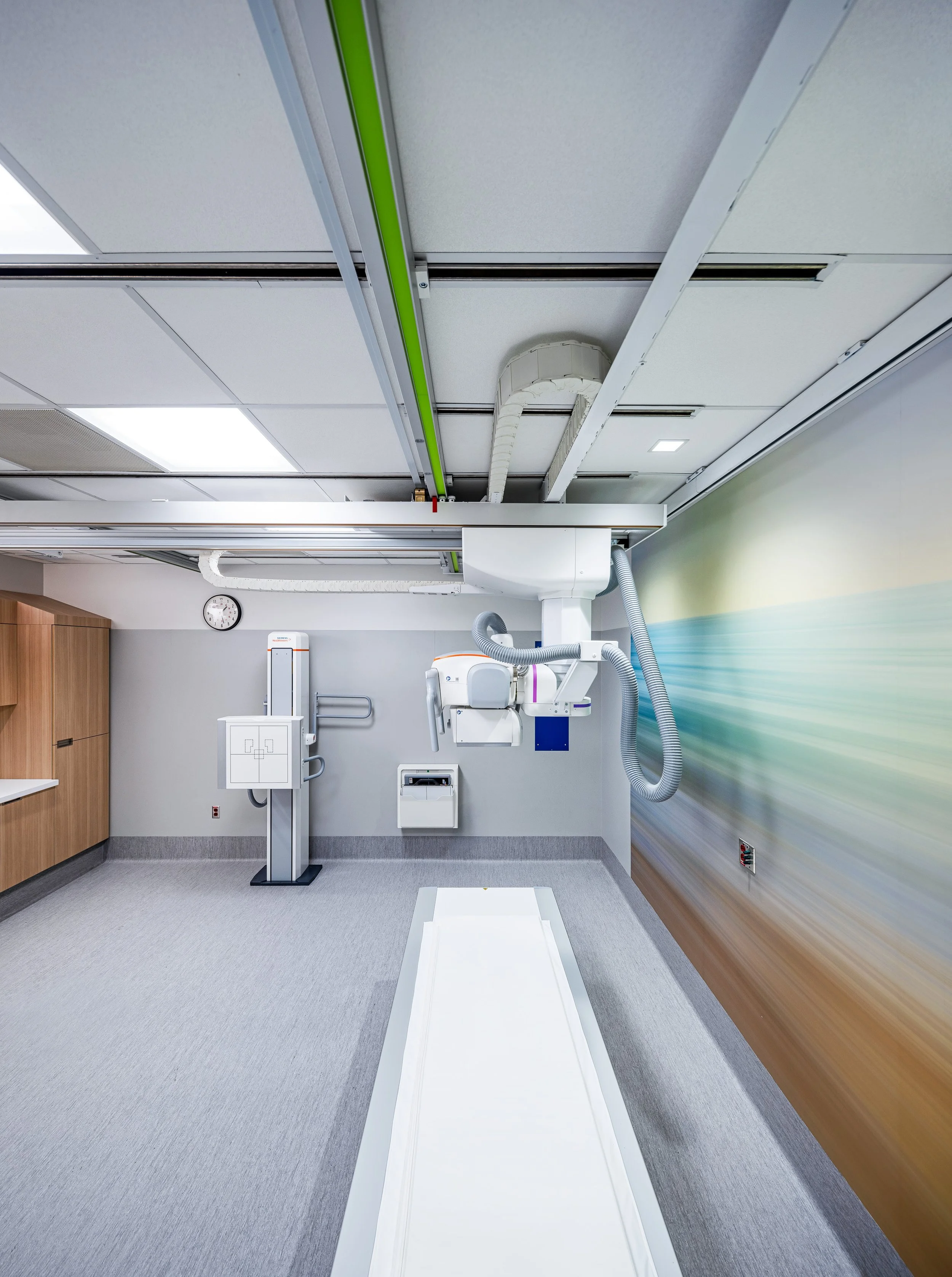 Detail view highlighting the ceiling-mounted X-ray system and integrated lighting within the imaging suite. The coordinated layout reflects careful collaboration between architectural design and medical technology requirements, ensuring precise funct